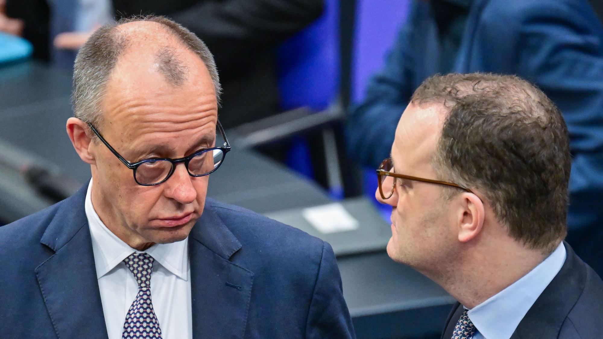 Bundeskanzler Friedrich Merz (CDU) spricht im Bundestag mit Jens Spahn.