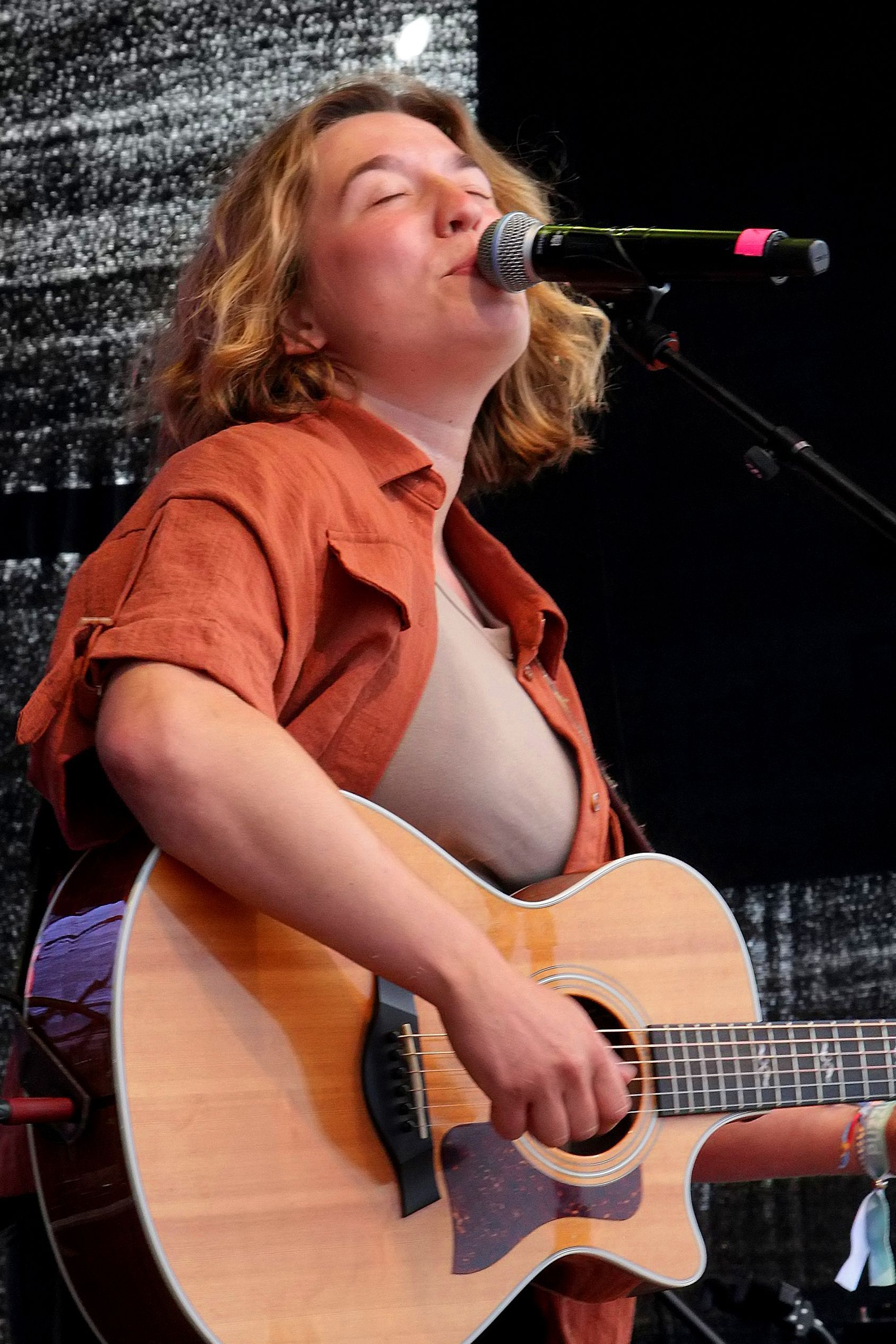 Auf dem Bild ist eine Musikerin mit Gitarre zu sehen.