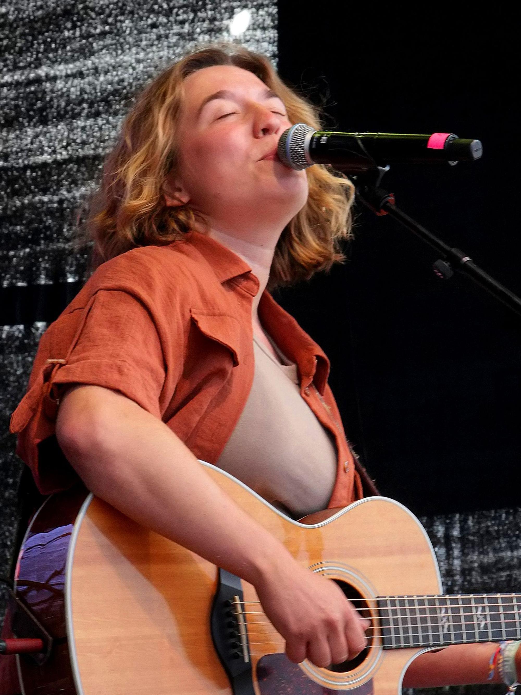 Auf dem Bild ist eine Musikerin mit Gitarre zu sehen.