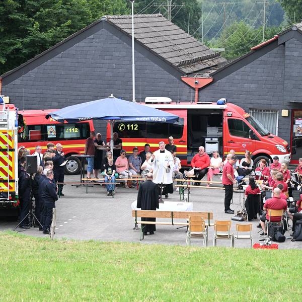 Zu sehen ist das Fest einer Feuerwehreinheit mit einem Pfarrer, der gerade spricht.