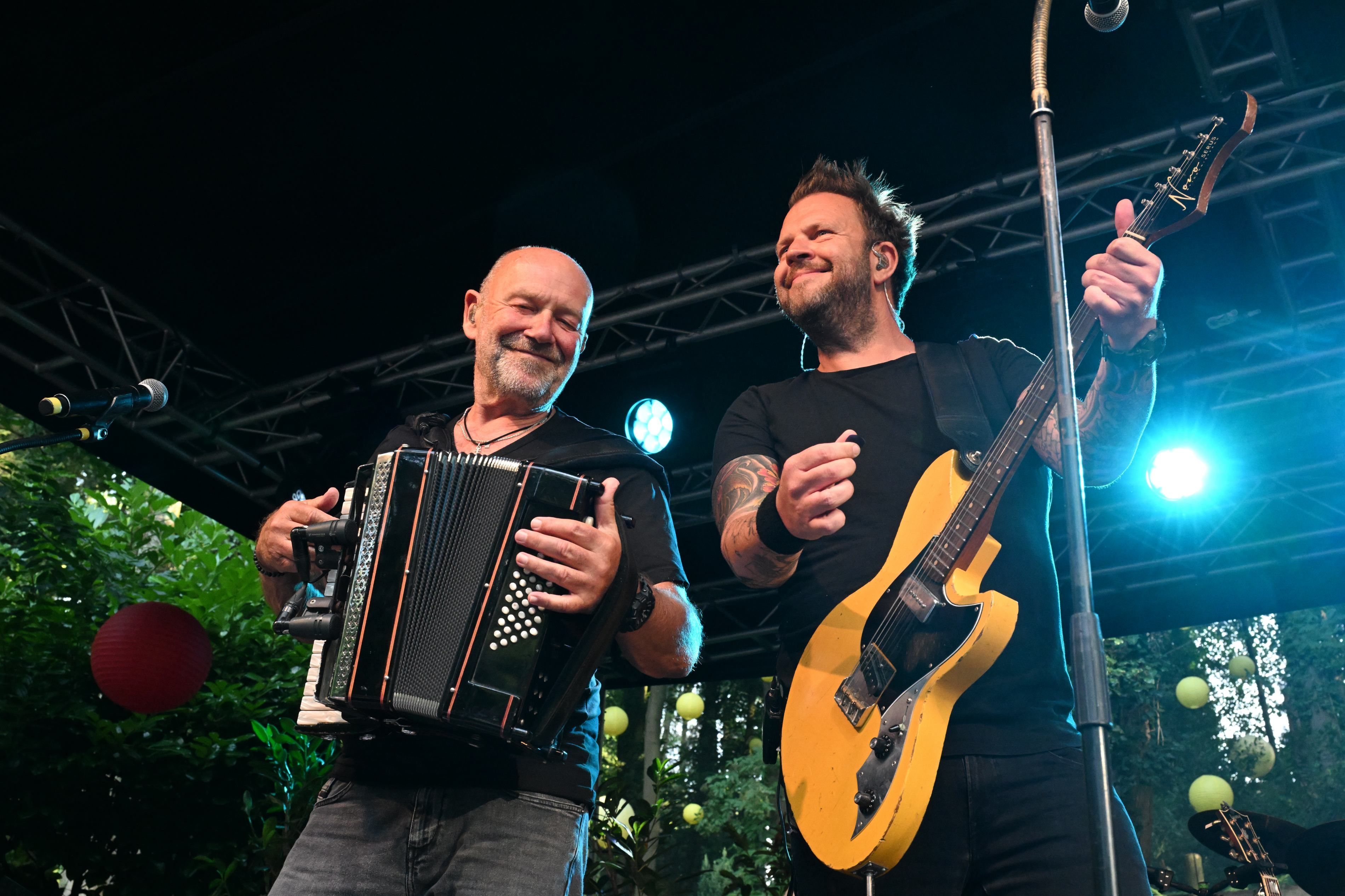 Zwei Männer stehen nebeneinander. Sie spielen Akkordeon und Gitarre.