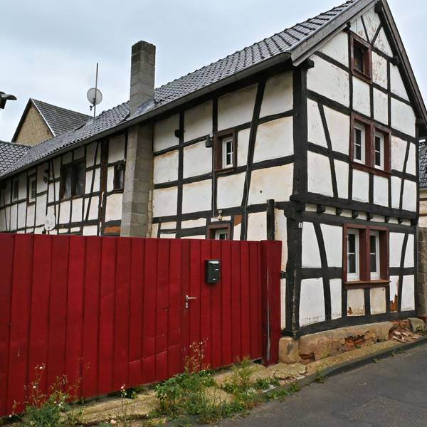 An der Agathastraße in Schaven steht ein sanierungsbedürftiges Fachwerkhaus mit einem roten Hoftor, das zu einem Dorfgemeinschaftshaus umgebaut werden soll.