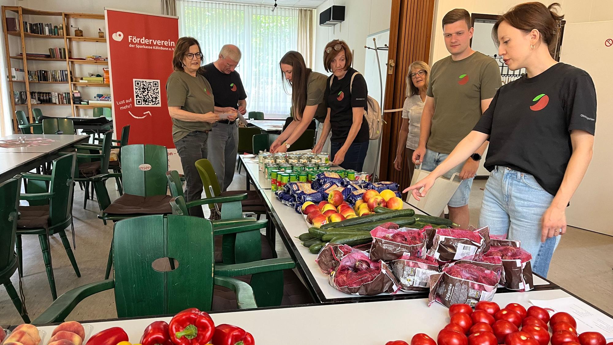 Obstkäppchen-Gründerin Carina Raddatz (r.) und das Unterstützungsteam beim Packen der Lebensmittelbeutel, die einmal im Monat zu bedürftigen Senioren in Porz gebracht werden.