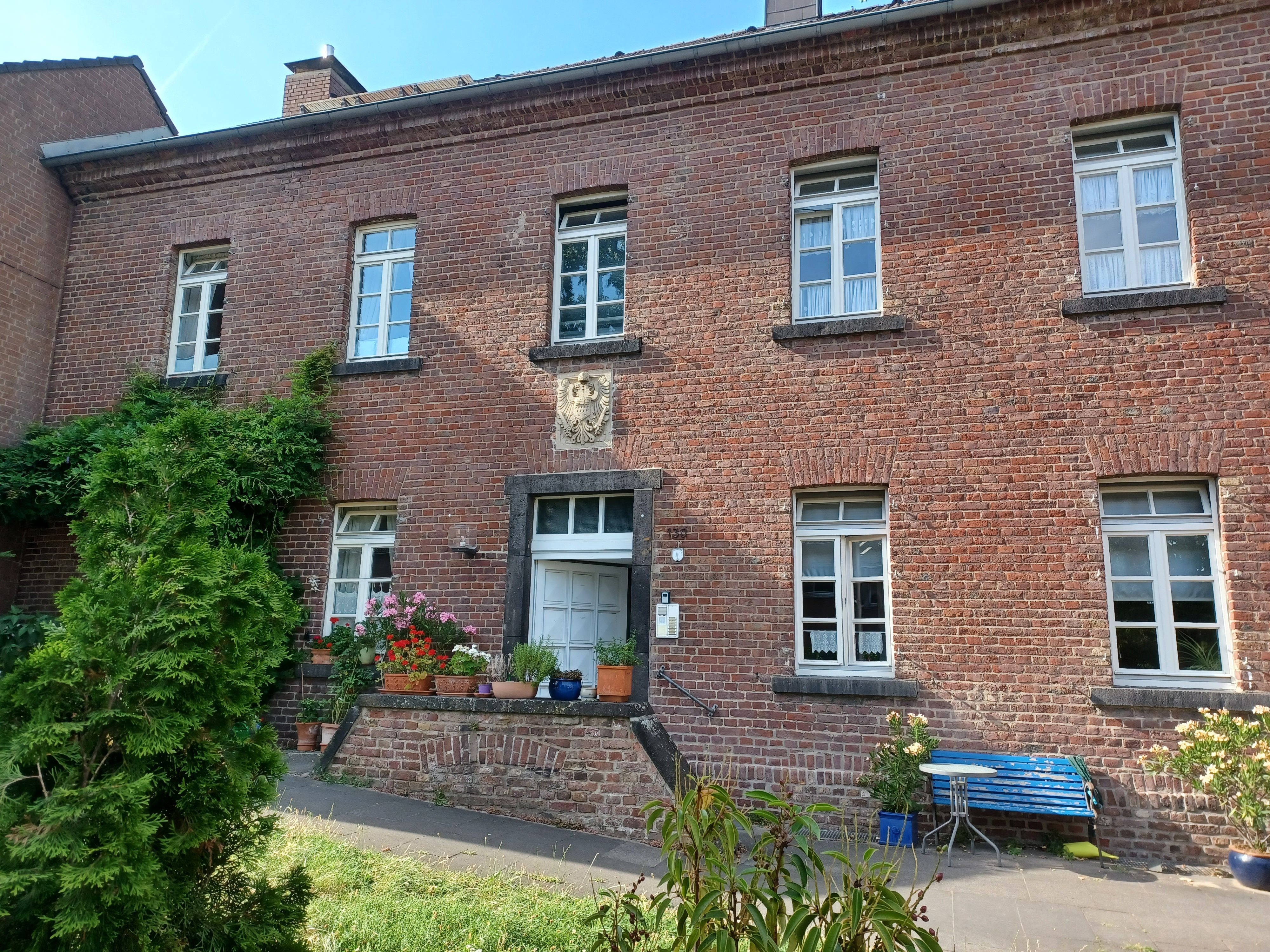 Ein zweigeschossiger Backsteinbau, der zu einem alten Gutshof gehörte, ist zu sehen.