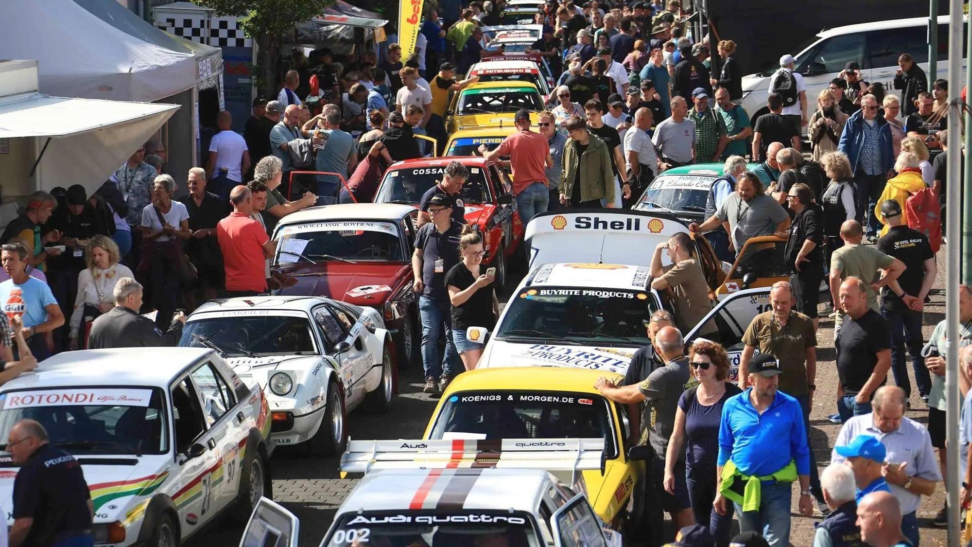 Bei der Rallye-Meile in der Dauner Innenstadt schlängeln sich zahlreiche Menschen durch die in Doppelreihe parkenden historischen Rennwagen.