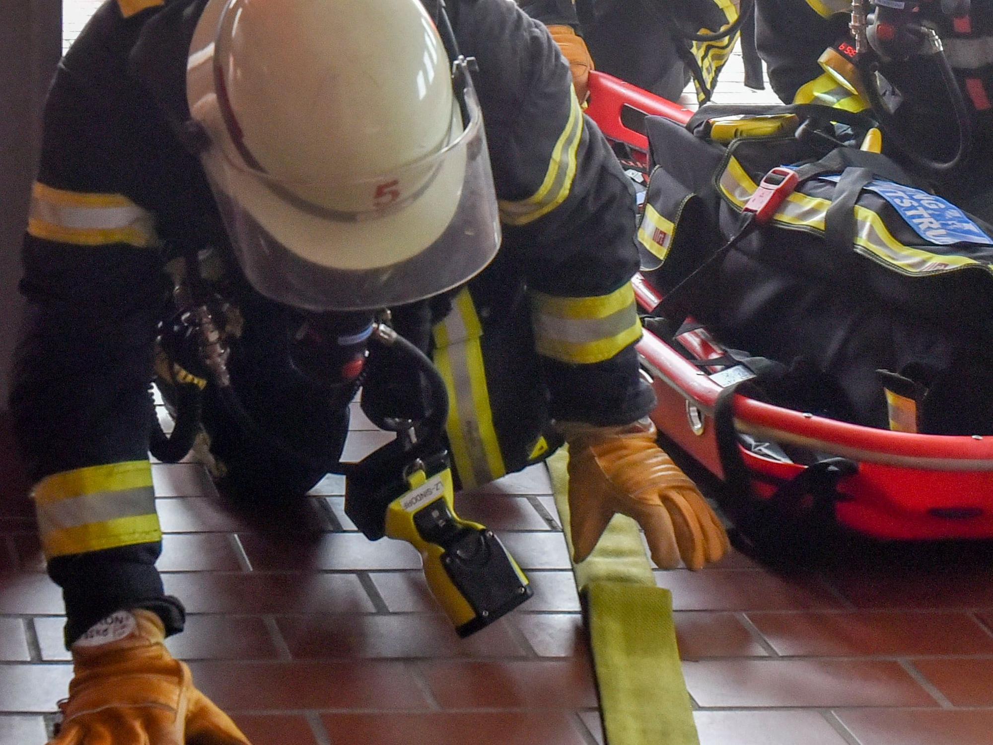 Das Bild zeigt Feuerwehrleute, die über den Boden robben.