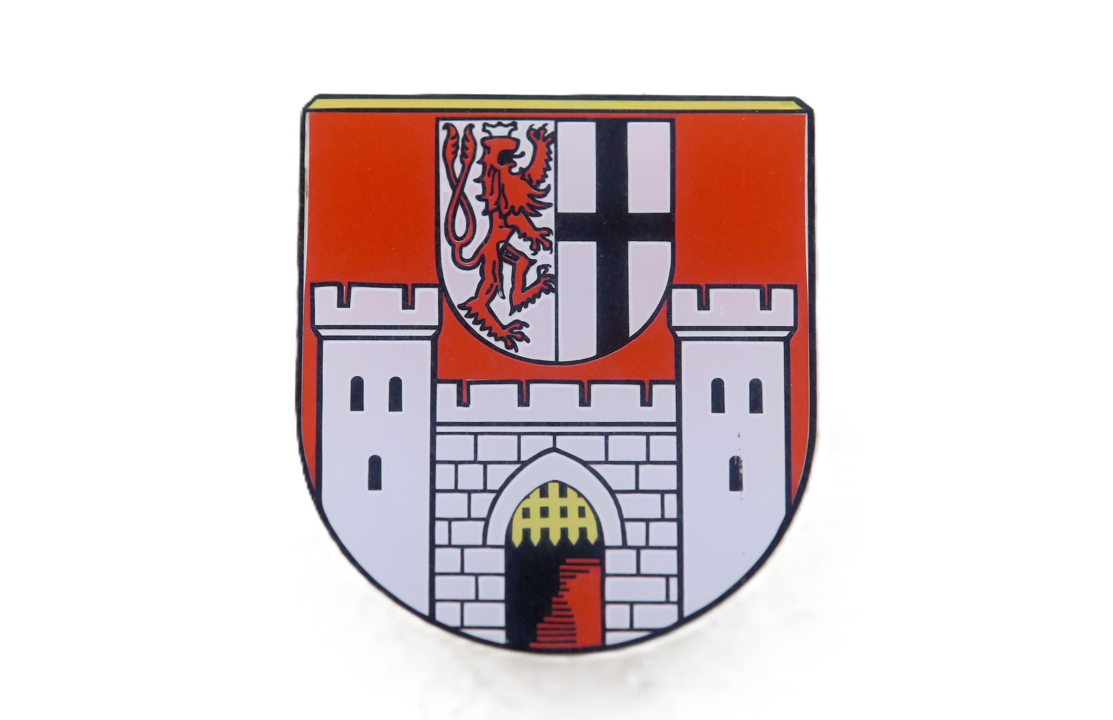 Das Wappen der Stadt Königswinter enthält eine Burg mit einem offenen Fallgatter und darüber ein Schild in dem links ein Bergischer Löwe in Richtung des Kurfürstenkreuzes nach rechts schaut.