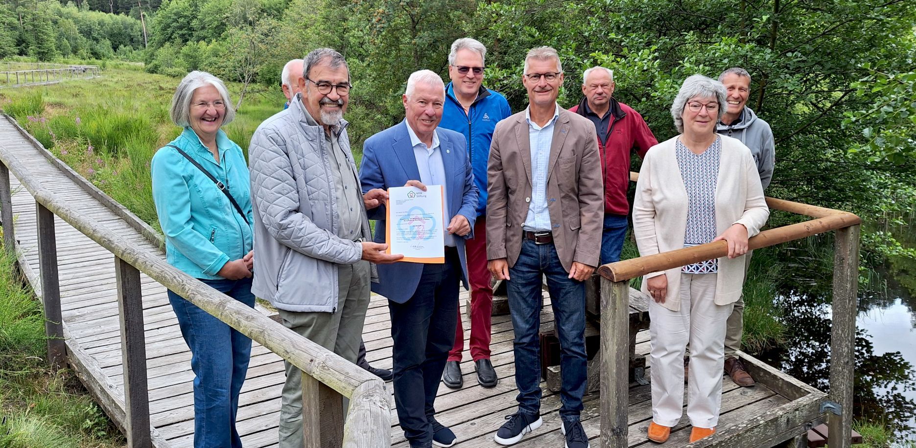 Eine Gruppe Männer und Frauen steht auf einer Plattform des Moorpfads in Dahlem.