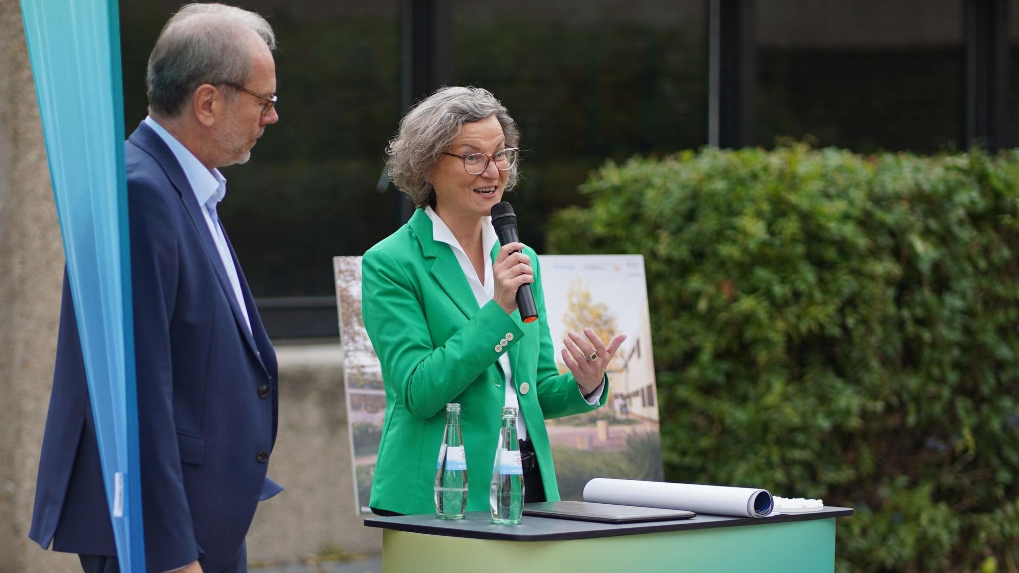 Das Foto zeigt eine Frau, die in ein Mikrofon spricht.