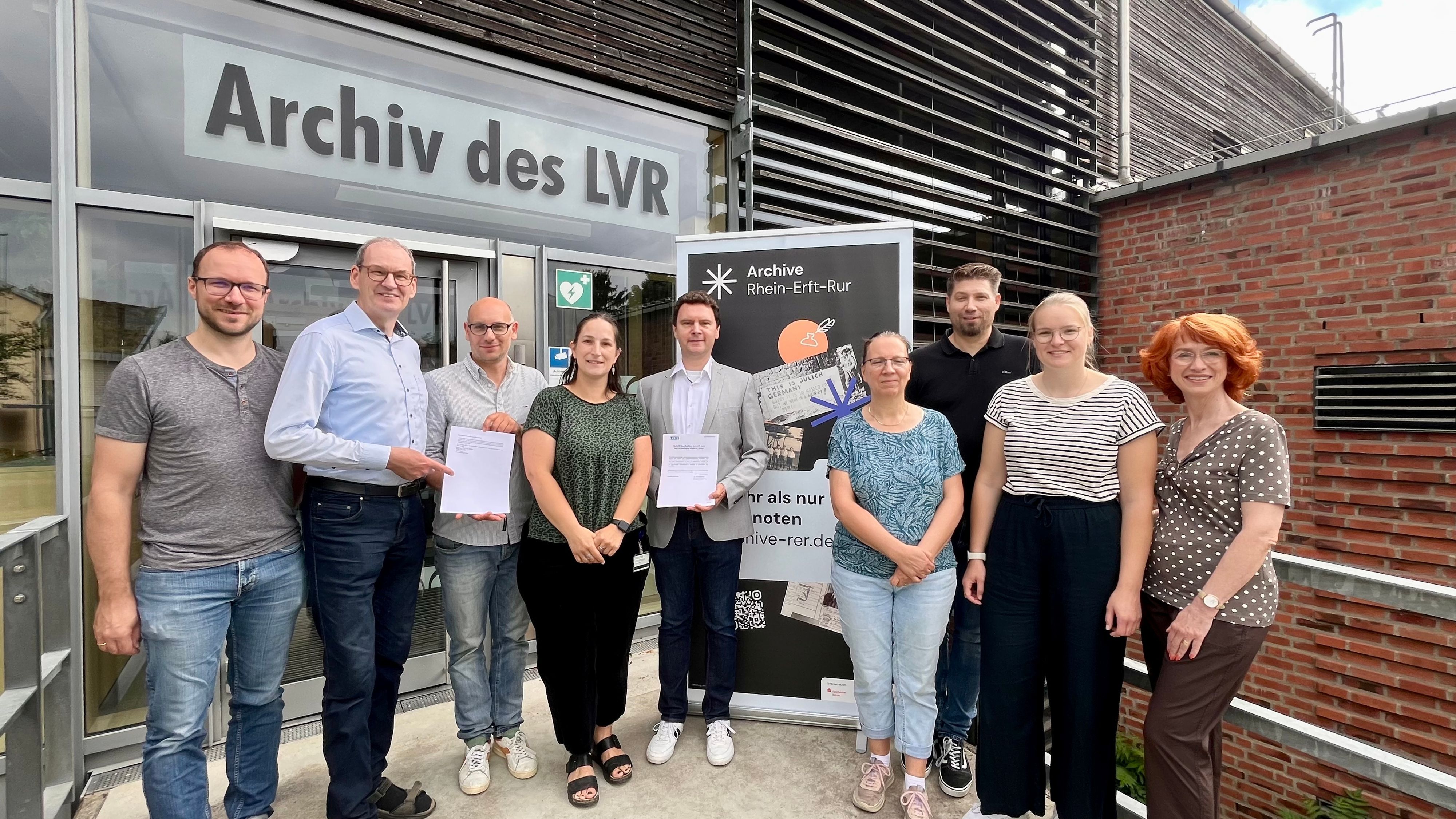 Frauen und Männer haben sich am Eingang des LVR-Archivs fürs Foto aufgestellt.