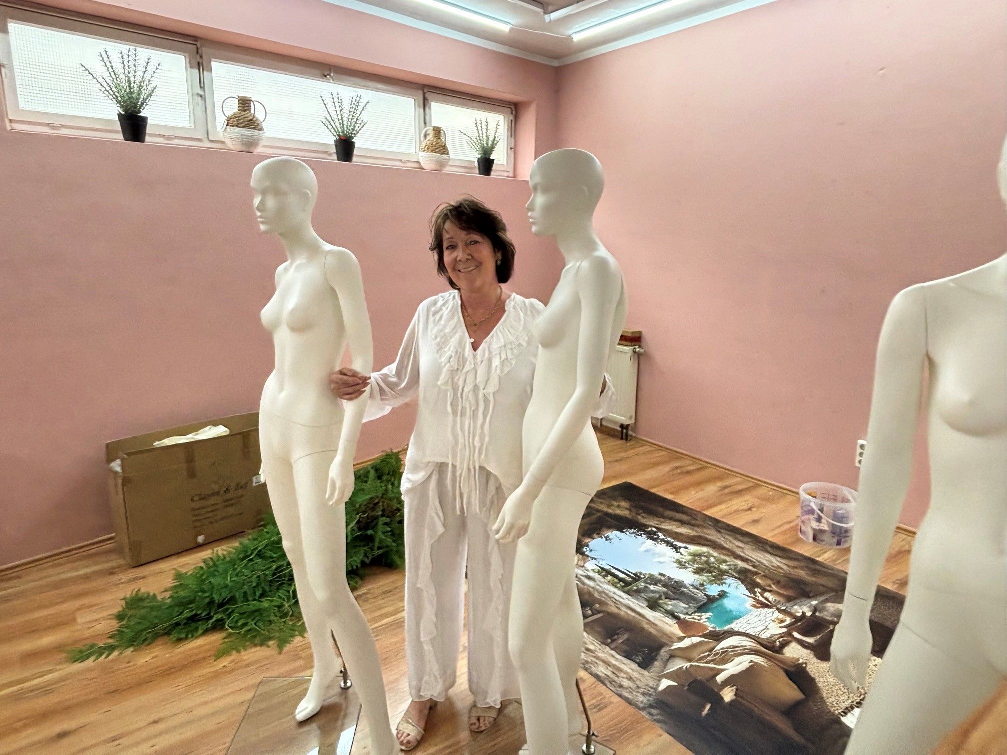 Auf dem Bild ist eine Frau zu sehen, die zwei Schaufensterpuppen umarmt.