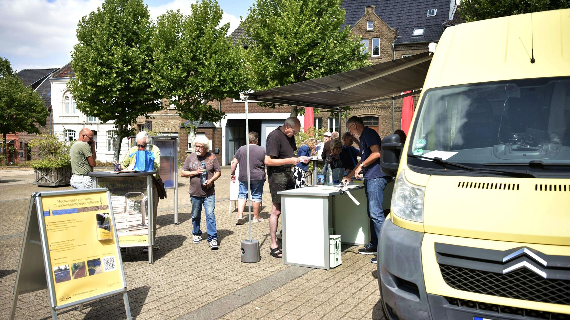 Menschen stehen in einer Schlange vor dem Wagen des VSR-Gewässerschutz, um Proben ihres Brunnenwassers abzugeben.