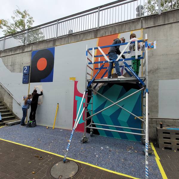 Jugendliche gestalten eine Wand mit bunten Farben.