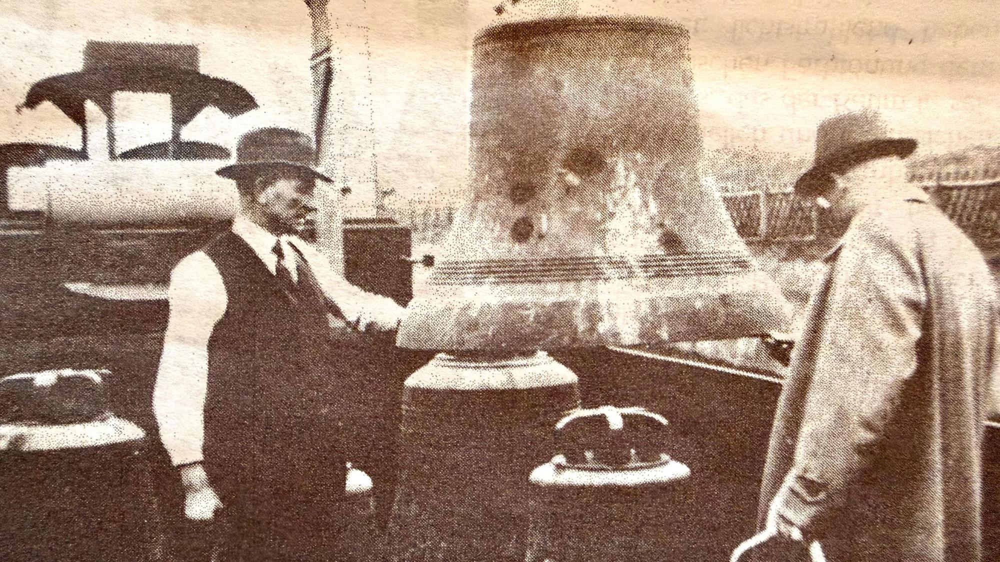 Das historische Bild zeigt zwei Männer, die eine Kirchenglocke verladen.