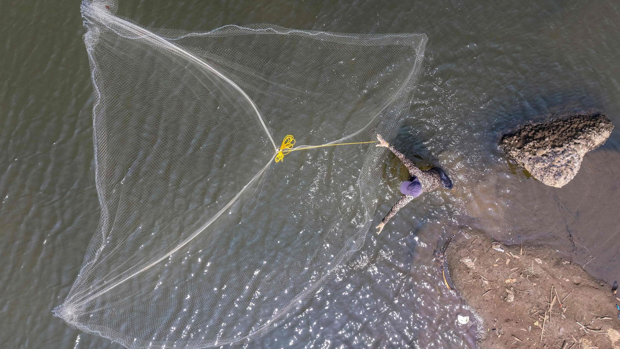 Fischer wirft sein Netz in einem Fluss in Tangerang auf der indonesischen Insel Java. Wegen des El-Niño-Phänomens ist der Wasserstand gesunken. Die anhaltende Trockenzeit verschärft die Dürre und bedroht in Teilen Indonesiens die Ernährungssicherheit.