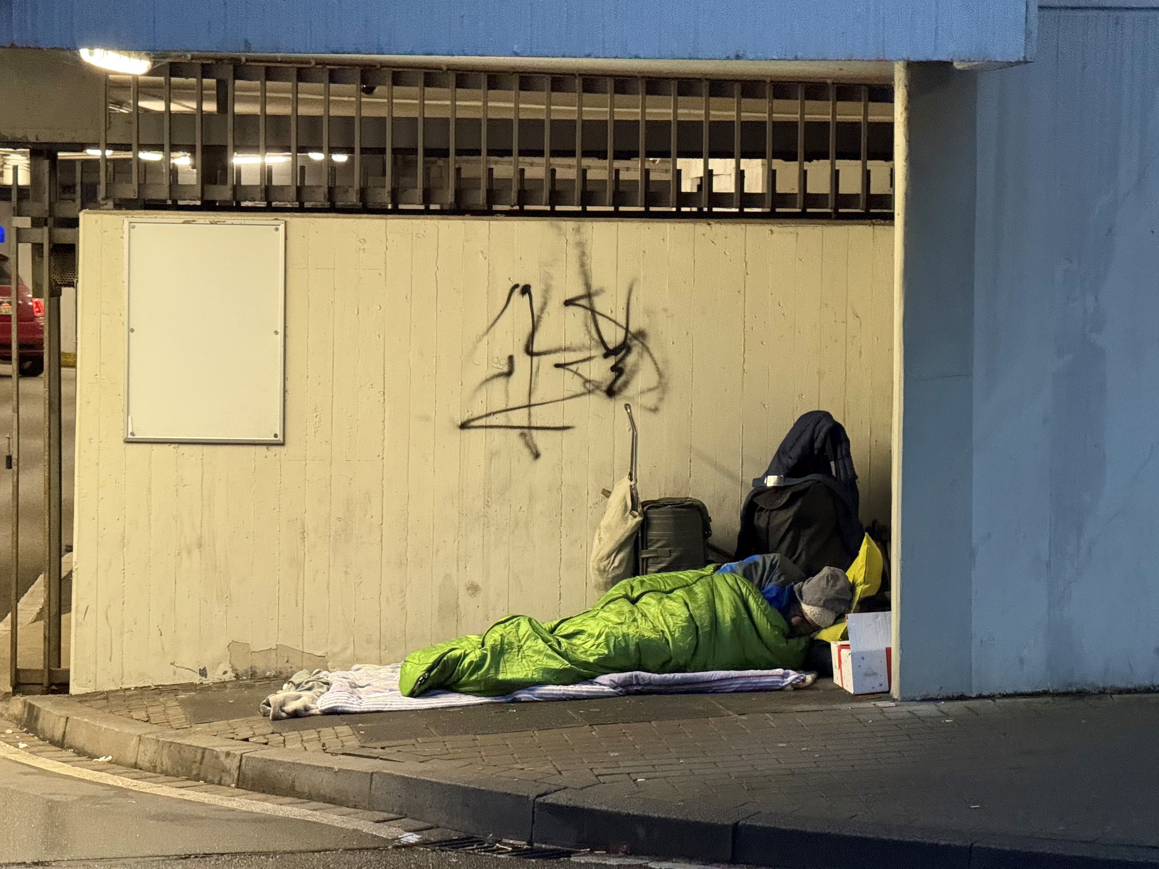 Das Bild zeigt einen Obdachlosen in einem Schlafsack.