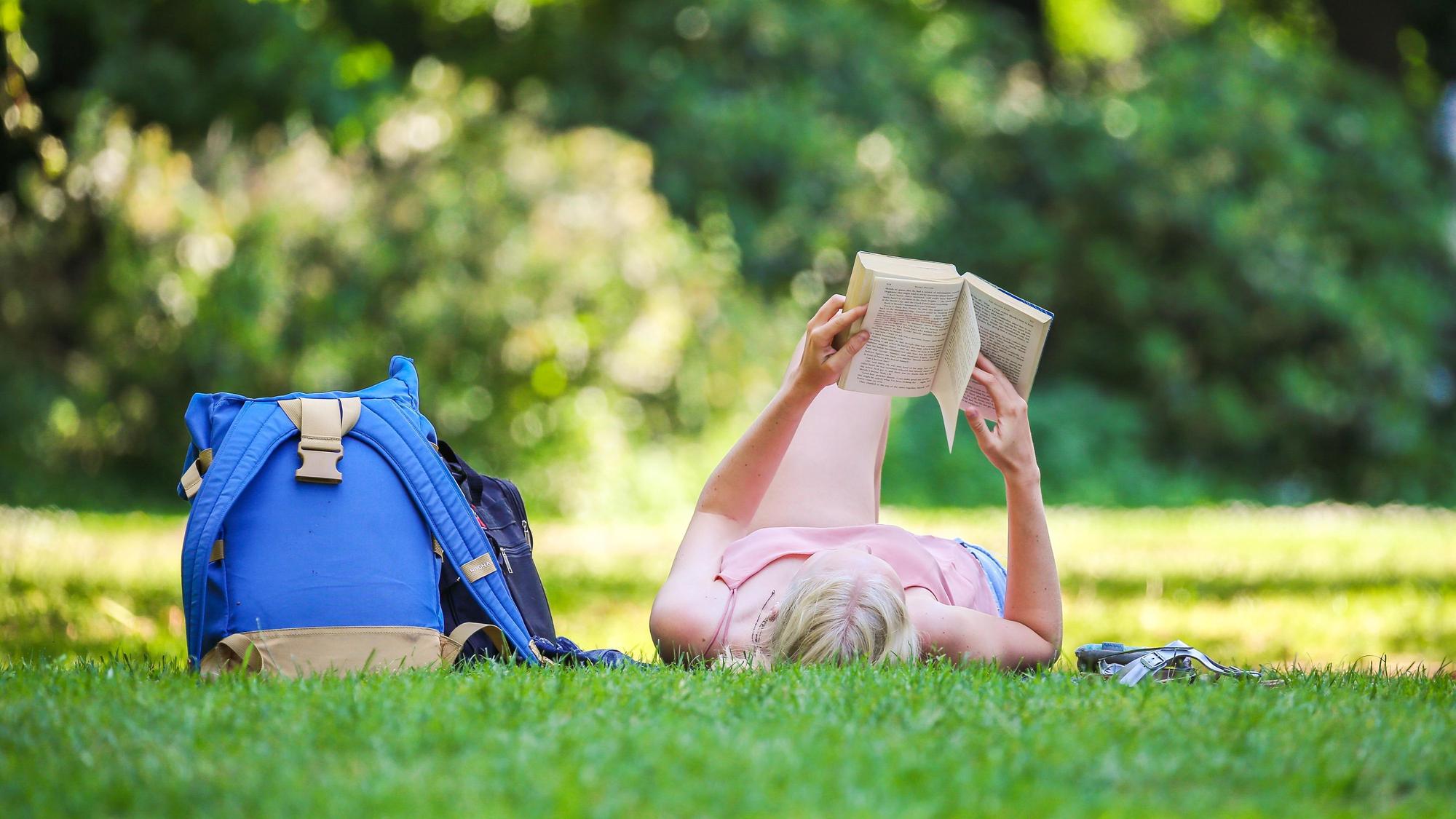 Eine Frau liest ein Buch in einem Park.