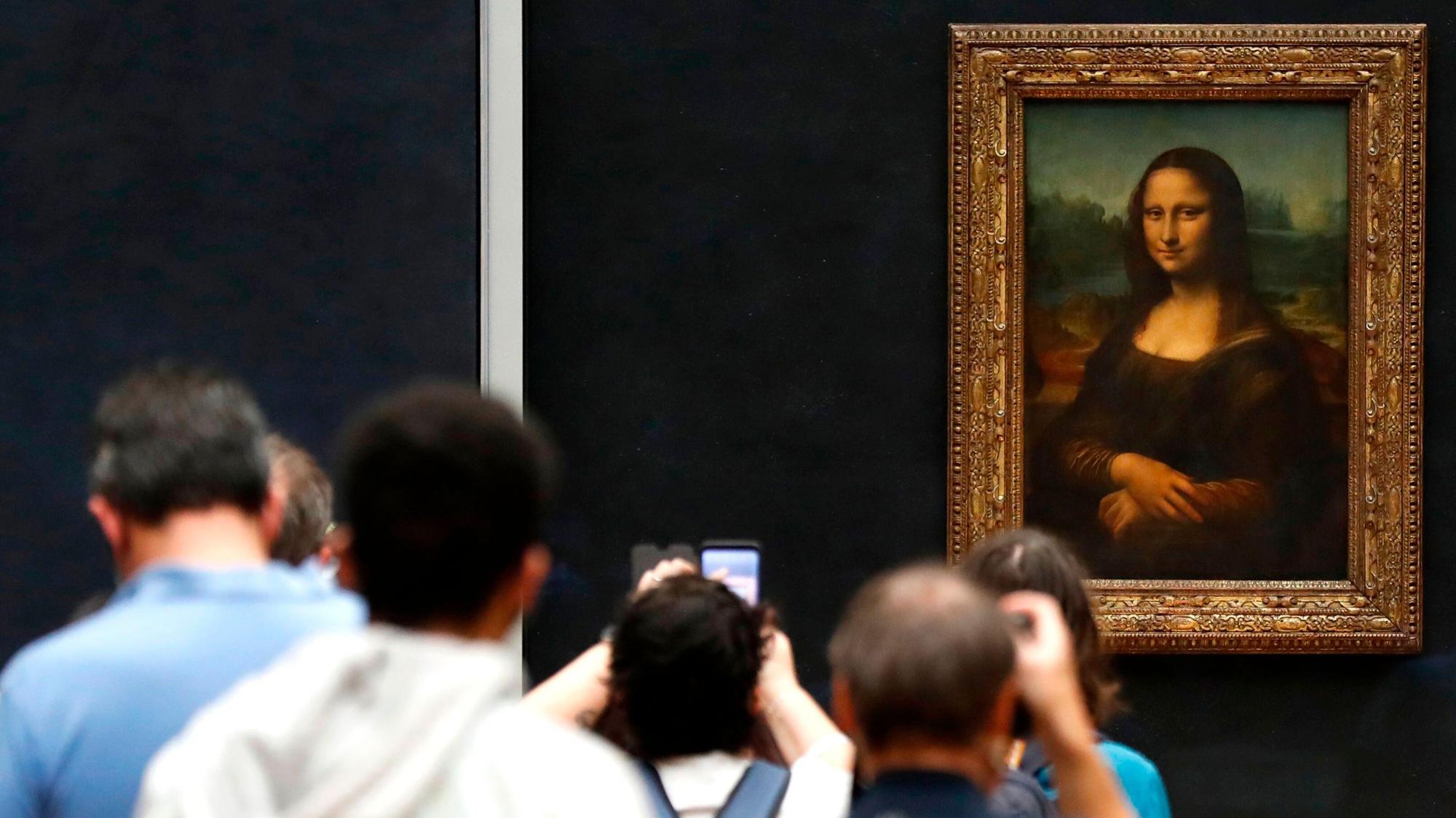 Besucher machen Fotos vor Leonardo da Vincis Meisterwerk "Mona Lisa" im Louvre-Museum.