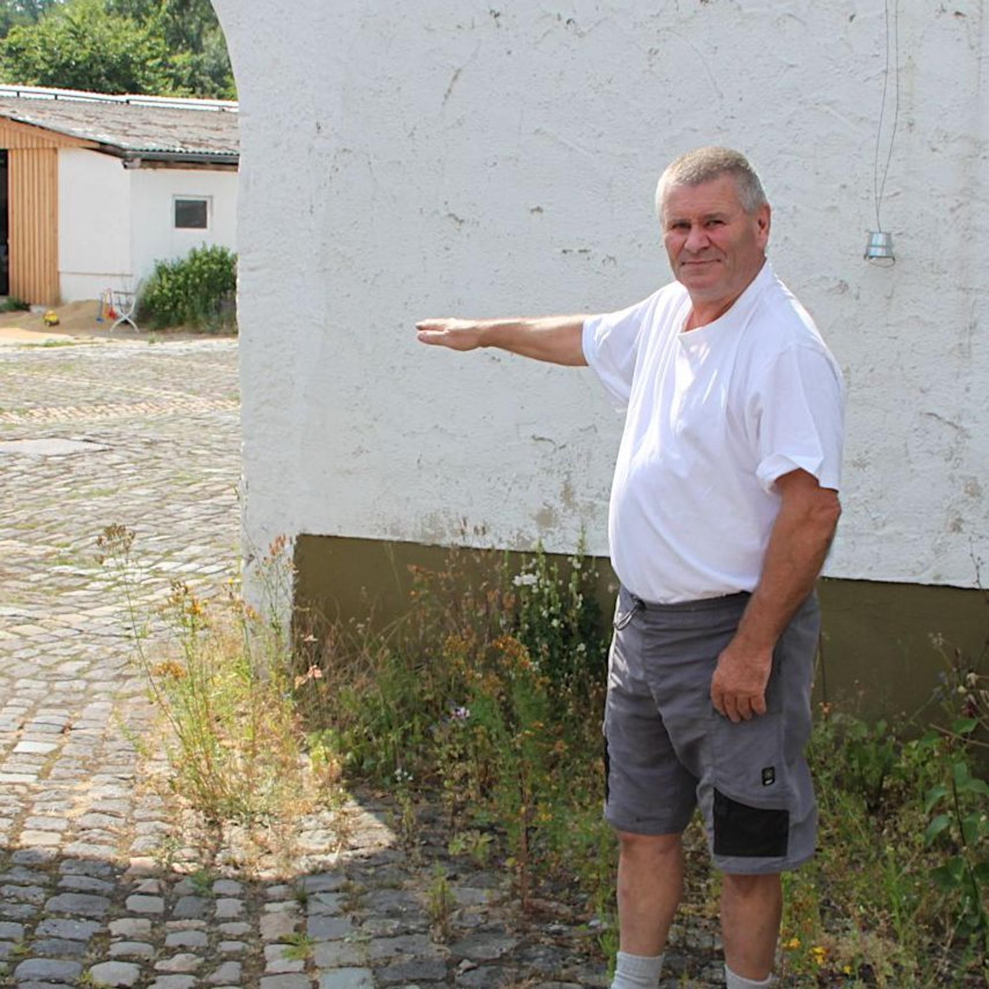 Josef Reuter zeigt an der Einfahrt zu seinem Hof, wie hoch das Wasser 2021 dort stand.