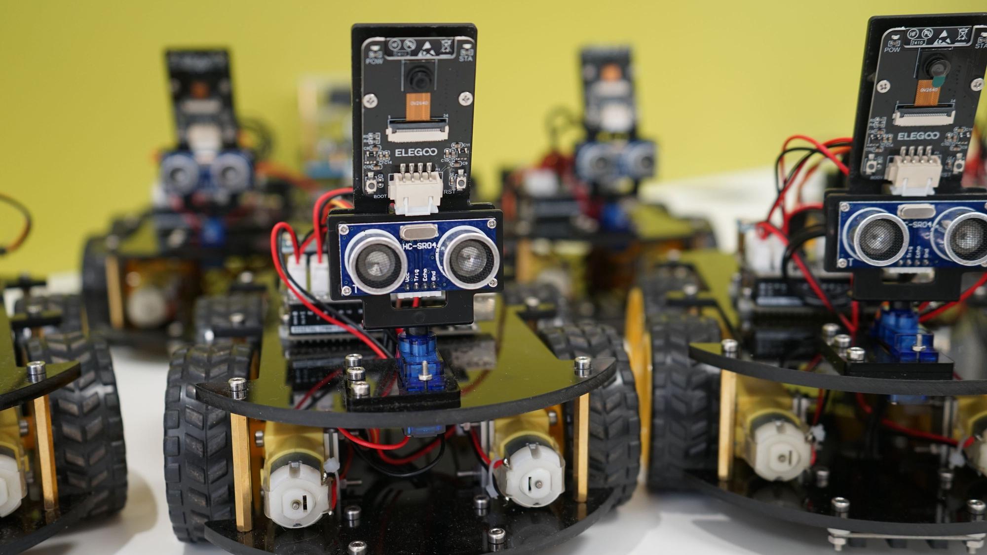 Roboter auf Rädern und mit Kameras stehen in einer Reihe.