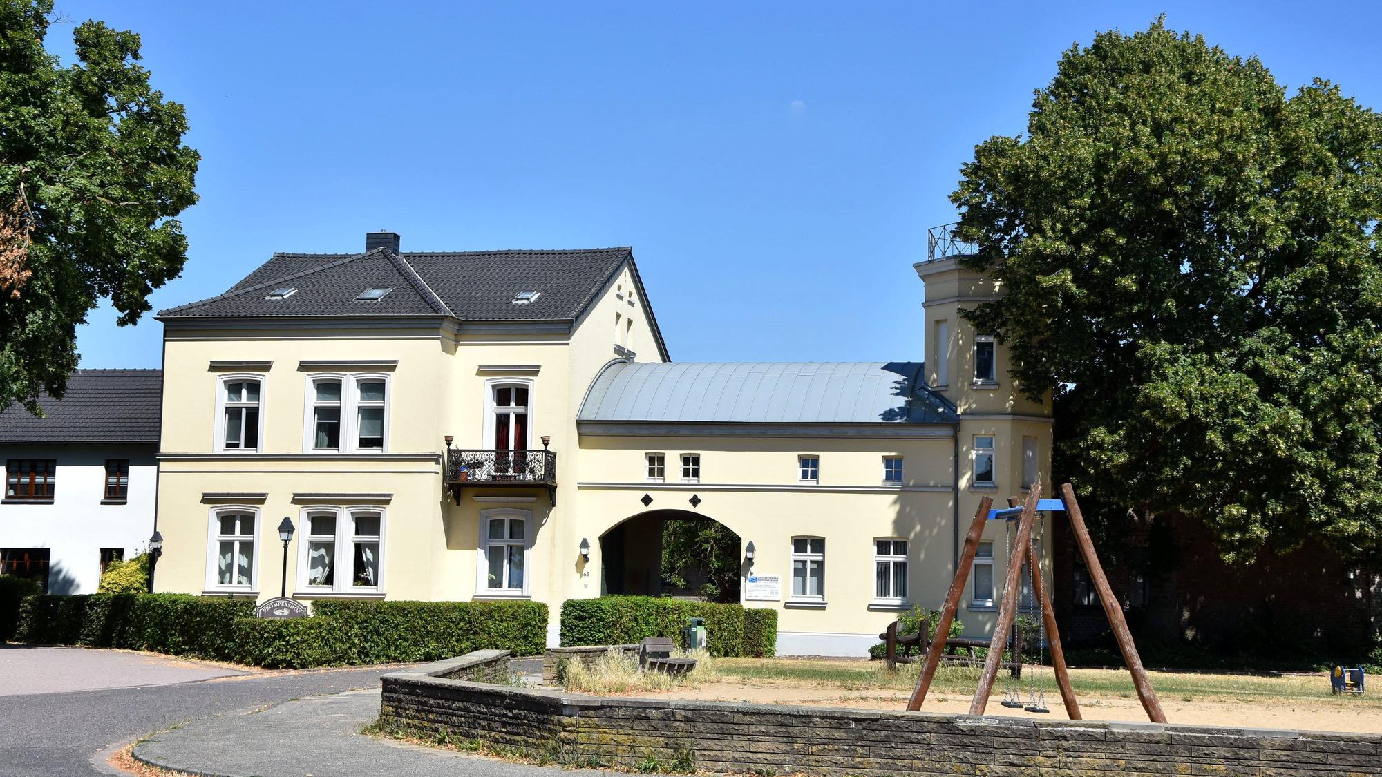 Zu sehen ist ein hellgelbes Haus, davor ein Spielplatz mit Schaukel.