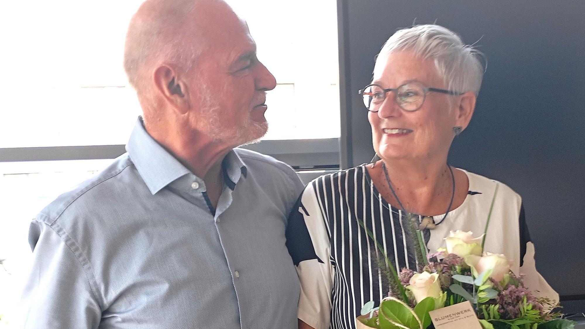 Das Foto zeigt eine Frau und einen Mann, sie hält Blumen in der Hand.