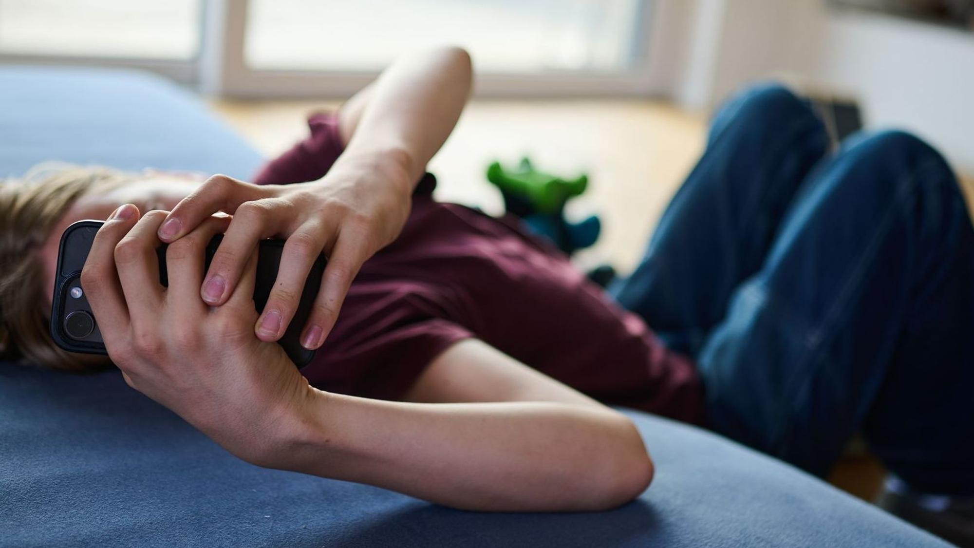 Ein Teenager guckt auf ein Handy.