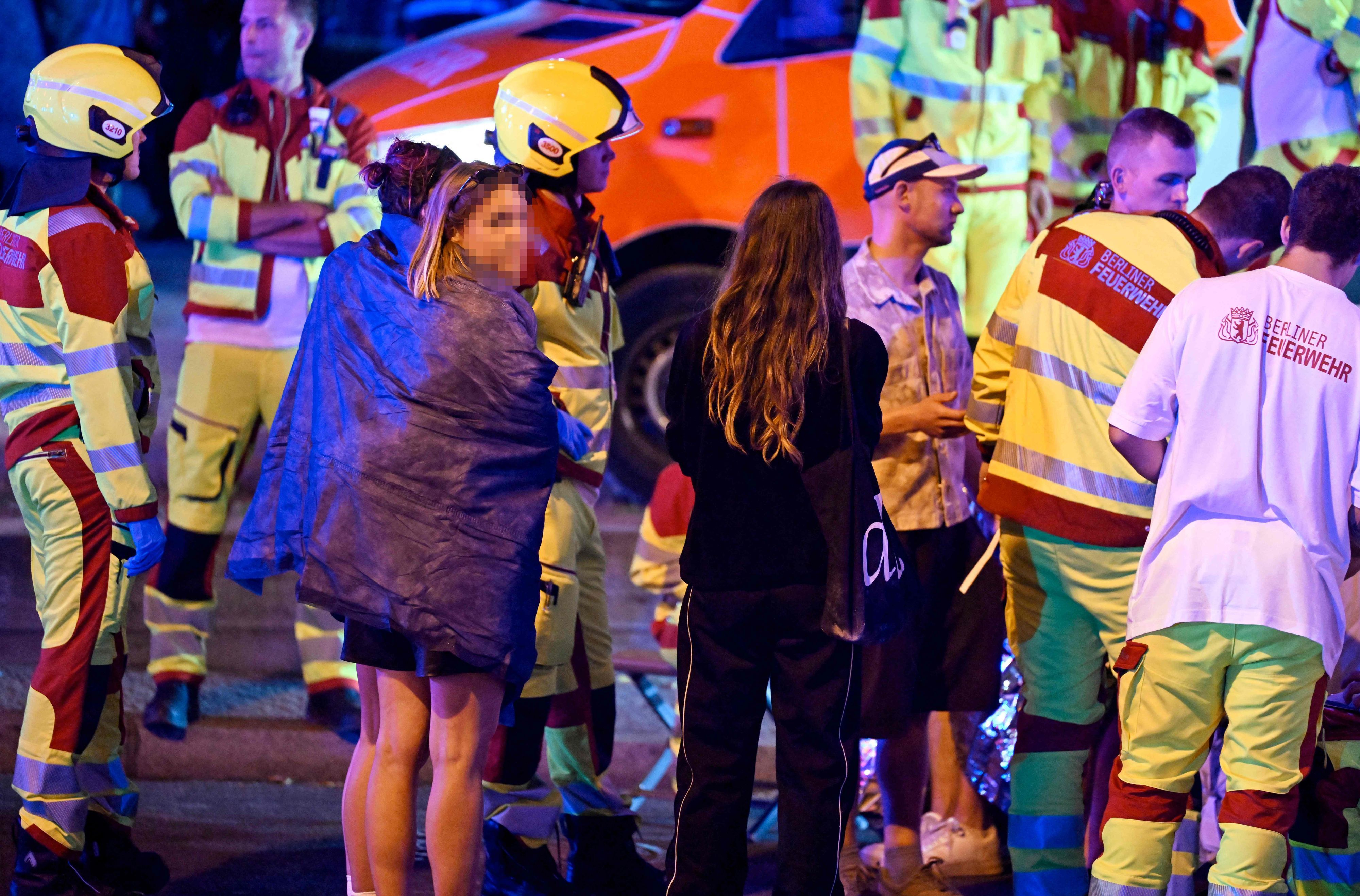 Rettungskräfte, Polizisten und weitere Menschen stehen in Berlin am Ort des Geschehens, an dem ein Mensch getötet und rund 15 weitere verletzt wurden. Nach bisherigen Erkenntnissen war ein Auto am Rande der Christopher-Street-Day-Parade (CSD) mutmaßlich in eine Menschenmenge gefahren.