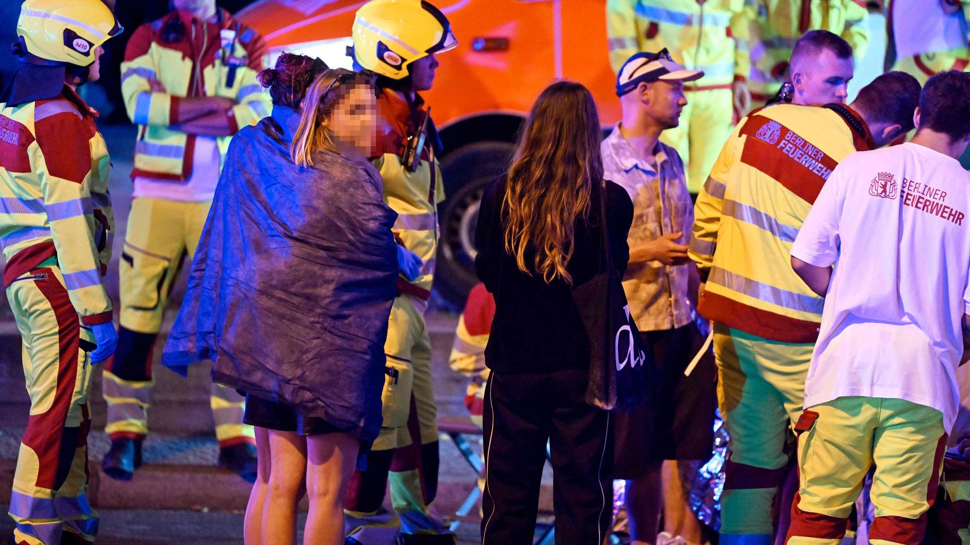 Rettungskräfte, Polizisten und weitere Menschen stehen in Berlin am Ort des Geschehens, an dem ein Mensch getötet und rund 15 weitere verletzt wurden. Nach bisherigen Erkenntnissen war ein Auto am Rande der Christopher-Street-Day-Parade (CSD) mutmaßlich in eine Menschenmenge gefahren.