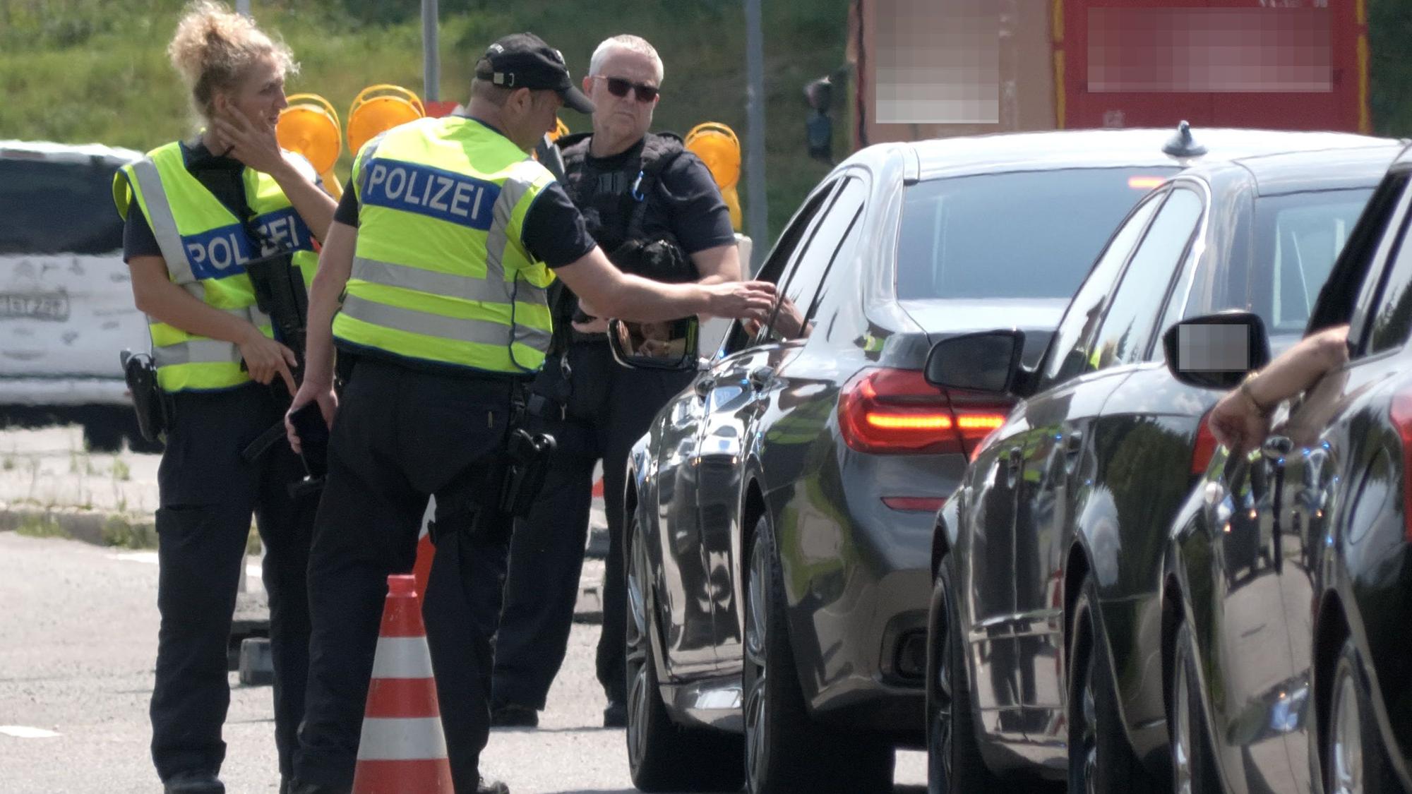 Polizisten kontrollieren am Grenzübergang nach Tschechien die Fahrzeuge. Nach dem Tatverdächtigen für den mutmaßlichen Terroranschlag am Rande des Christopher Street Day (CSD) in Berlin wird bundesweit gefahndet.