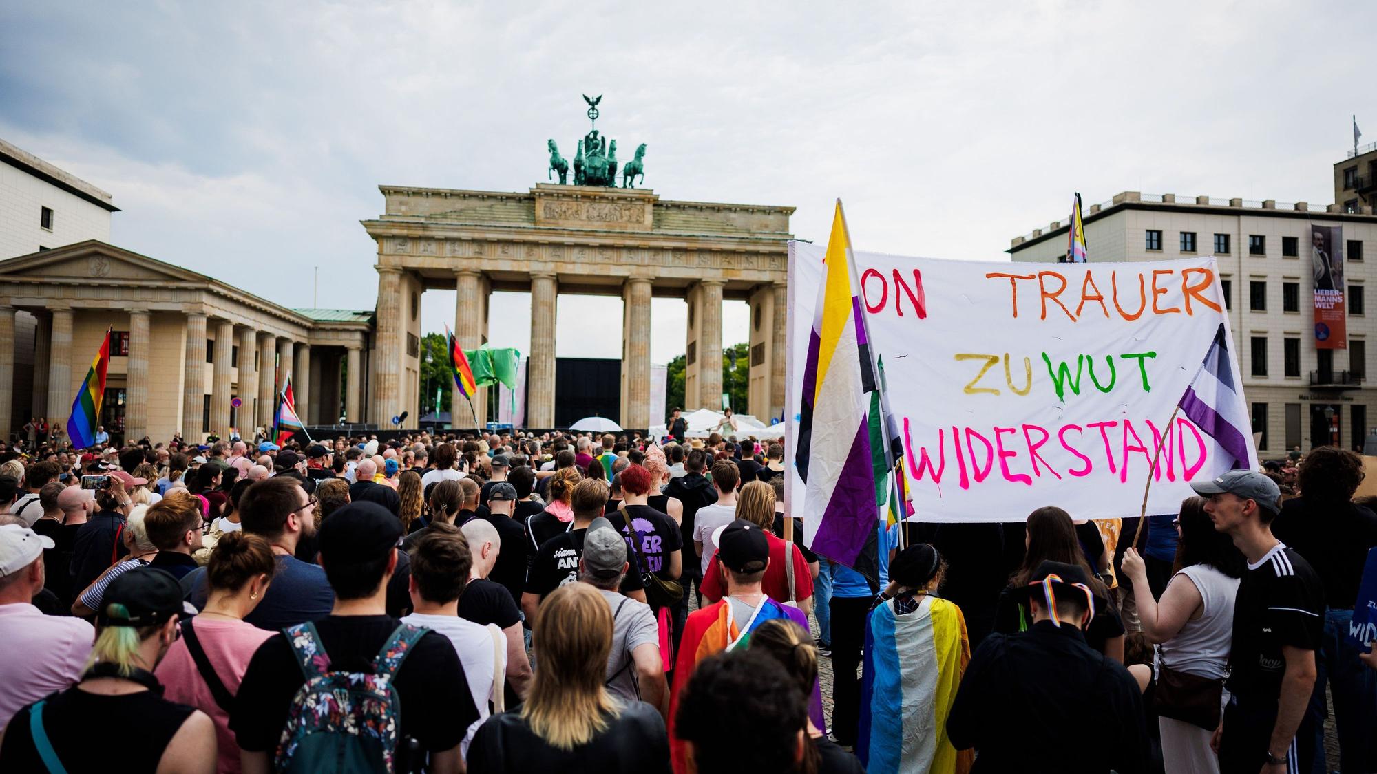Menschen trauern und demonstrieren vor dem Brandenburger Tor. Dabei wird ein Transparent mit der Aufschrift „Von Trauer zu Wut Widerstand!“ gehalten.