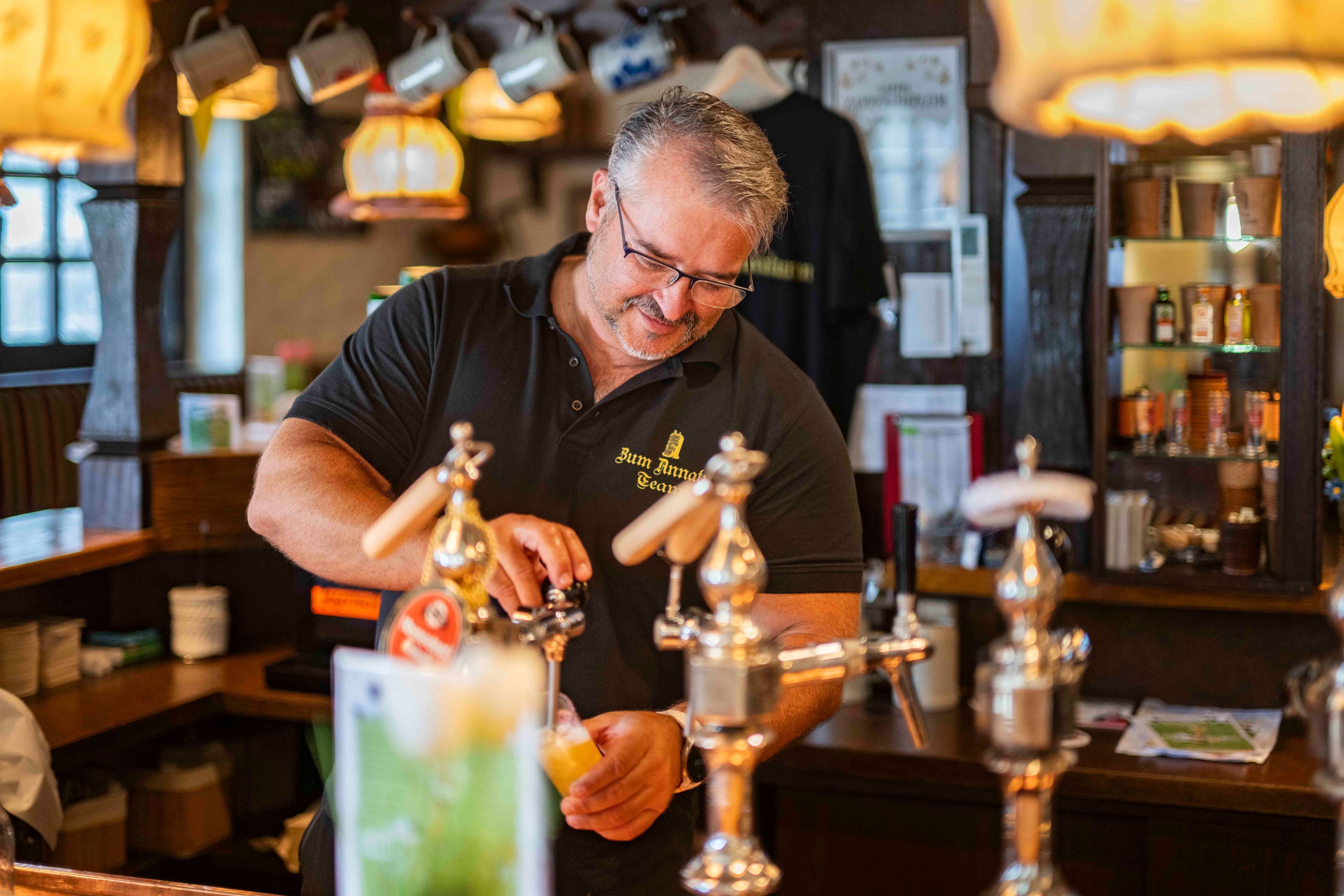 Das Bier zeigt Markus Tews hinter der Theke der Kneipe am Annaturmplatz.