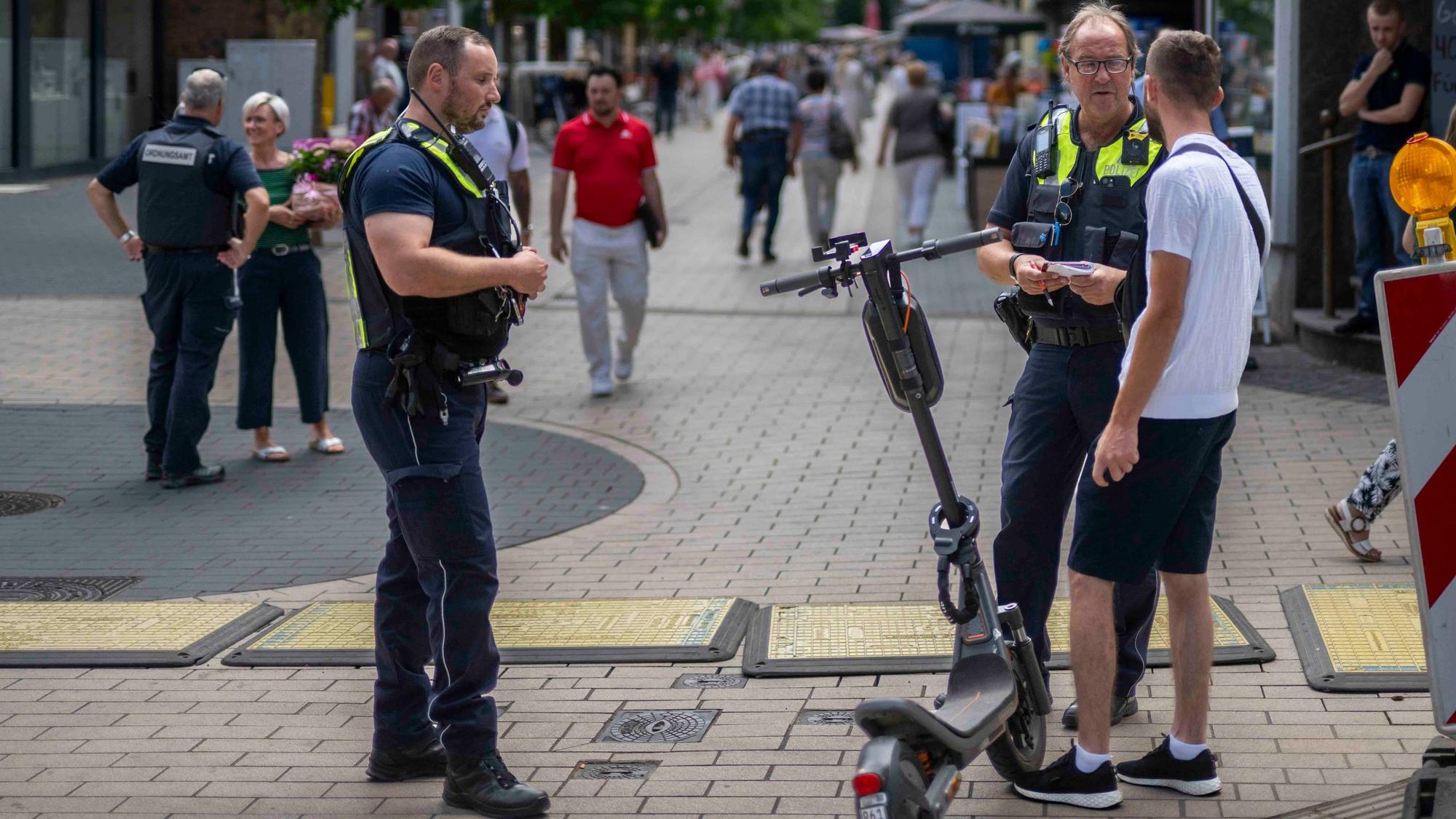 Das Bild zeigt einen Polizisten und einen Mitarbeiter des Euskirchener Ordnungsamts, wie sie gemeinsam einen E-Scooter-Fahrer kontrollieren.