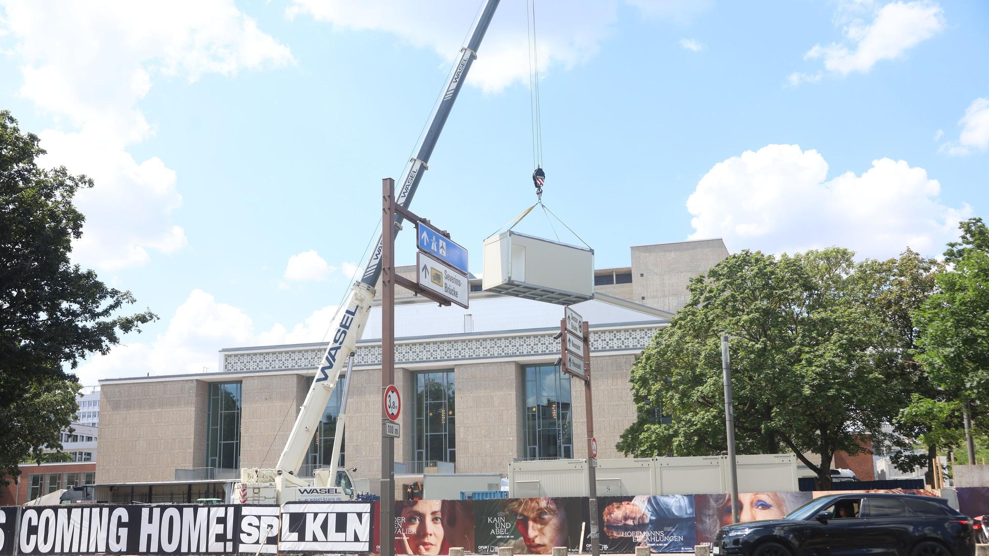 Die Baustelle an der Oper wird abgebaut. Die Container werden mit einem Kran verladen und sind mittlerweile verschwunden.