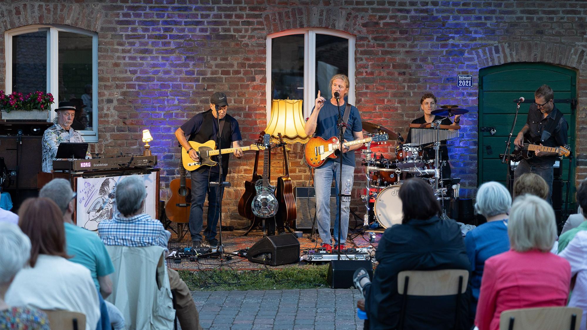 Kerk singt in ein Mikrofon, hinter ihm leuchtet eine Stehlampe.