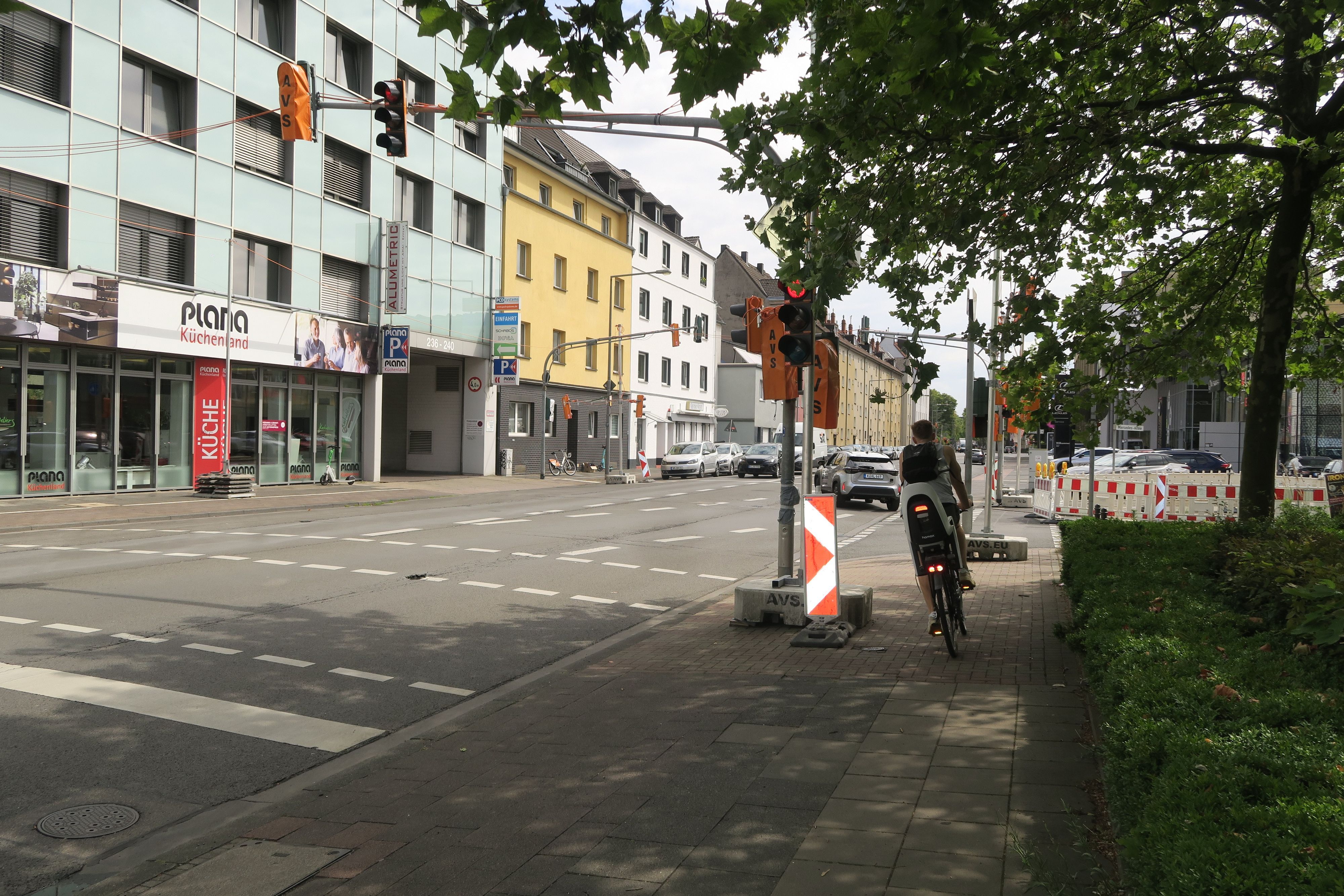 Ein Radfahrer fährt um den Betonsockel herum, der mitten auf dem Radweg platziert ist und eine Behelfsampel verankert.