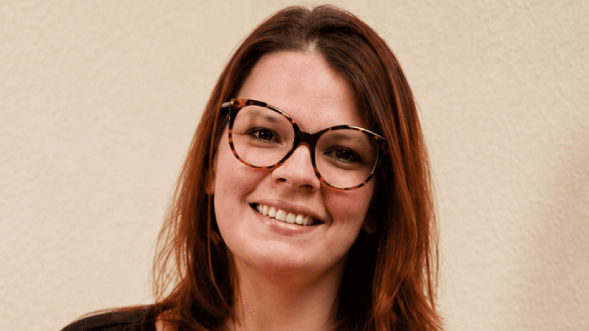 Das Bild zeigt Sandra Cornely. Sie lächelt, trägt eine Brille und hat lange, braune Haare.