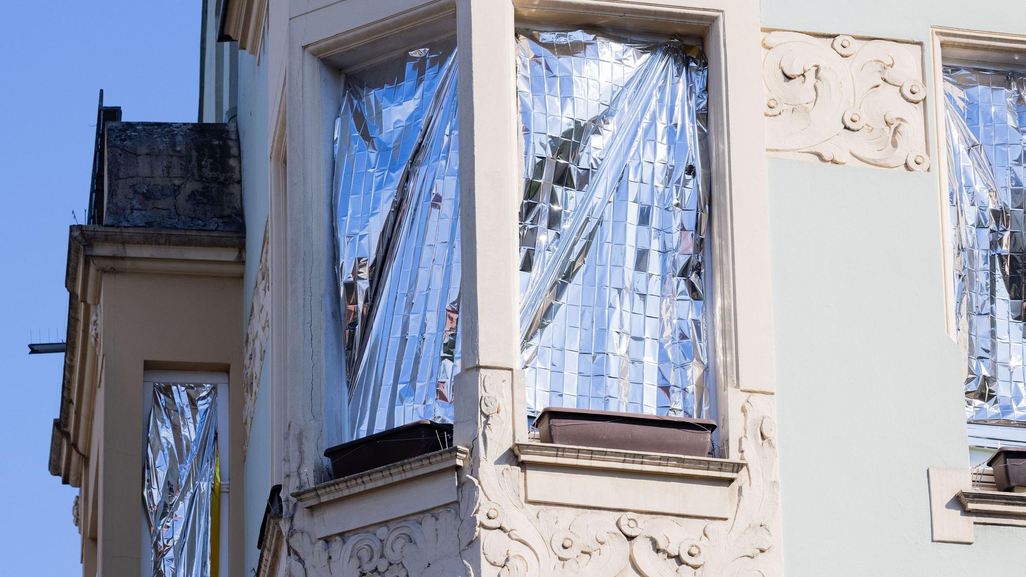Menschen schützen ihre Wohnungen in Köln mit Rettungsdecken, die mit Aluminium beschichtet sind, vor der Hitze und der Sonne.