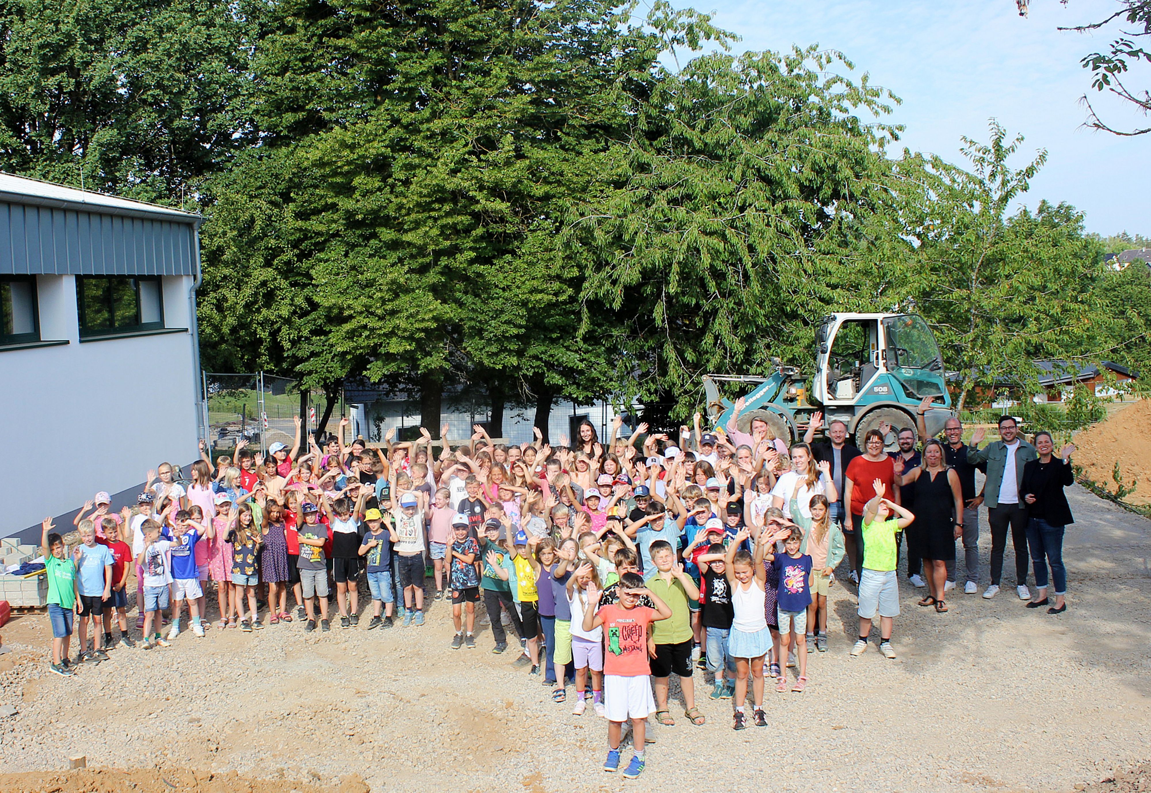 Viele Kinder und einige Erwachsene stehen auf dem Gelände, wo der Soccer-Court angelegt wird.