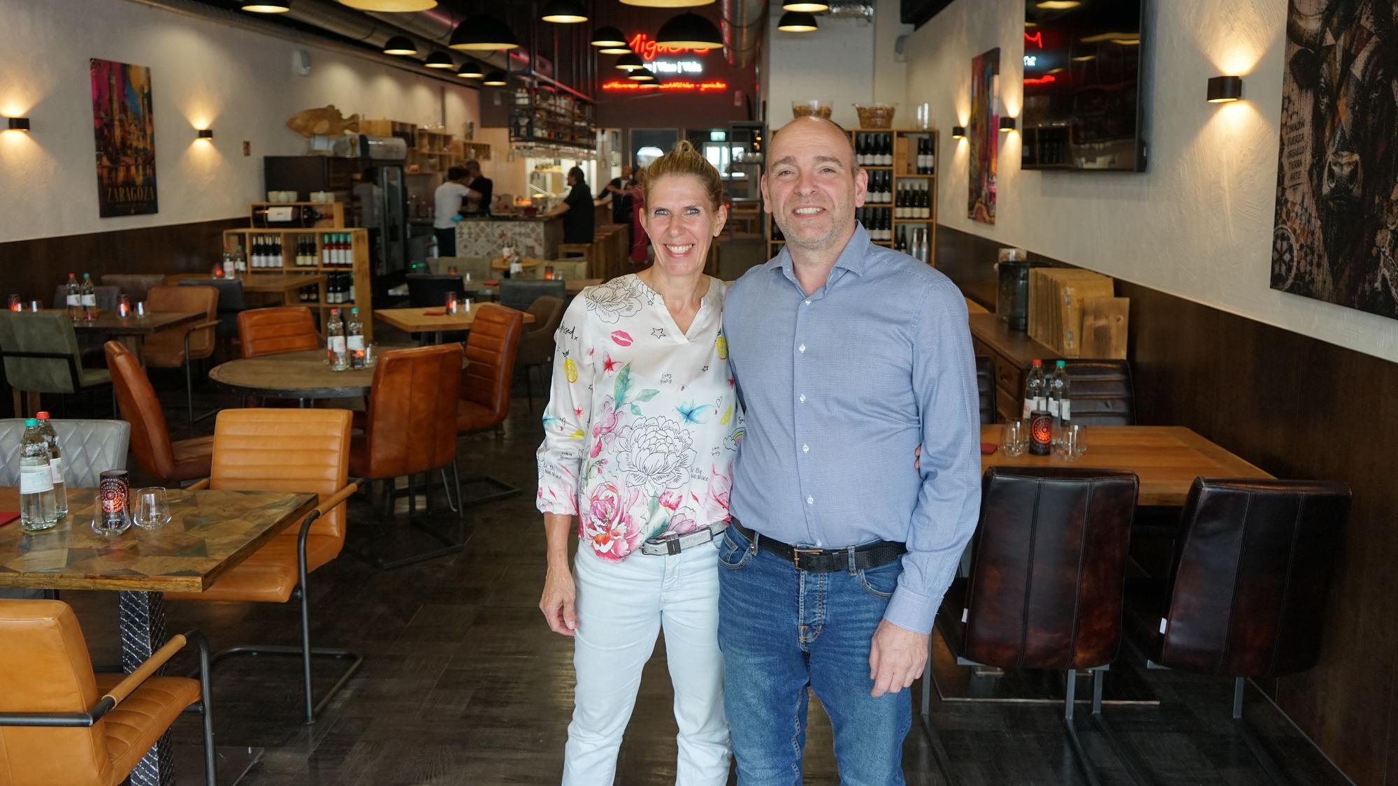 Eine Frau und ein Mann stehen in einem Restaurant und lächeln.