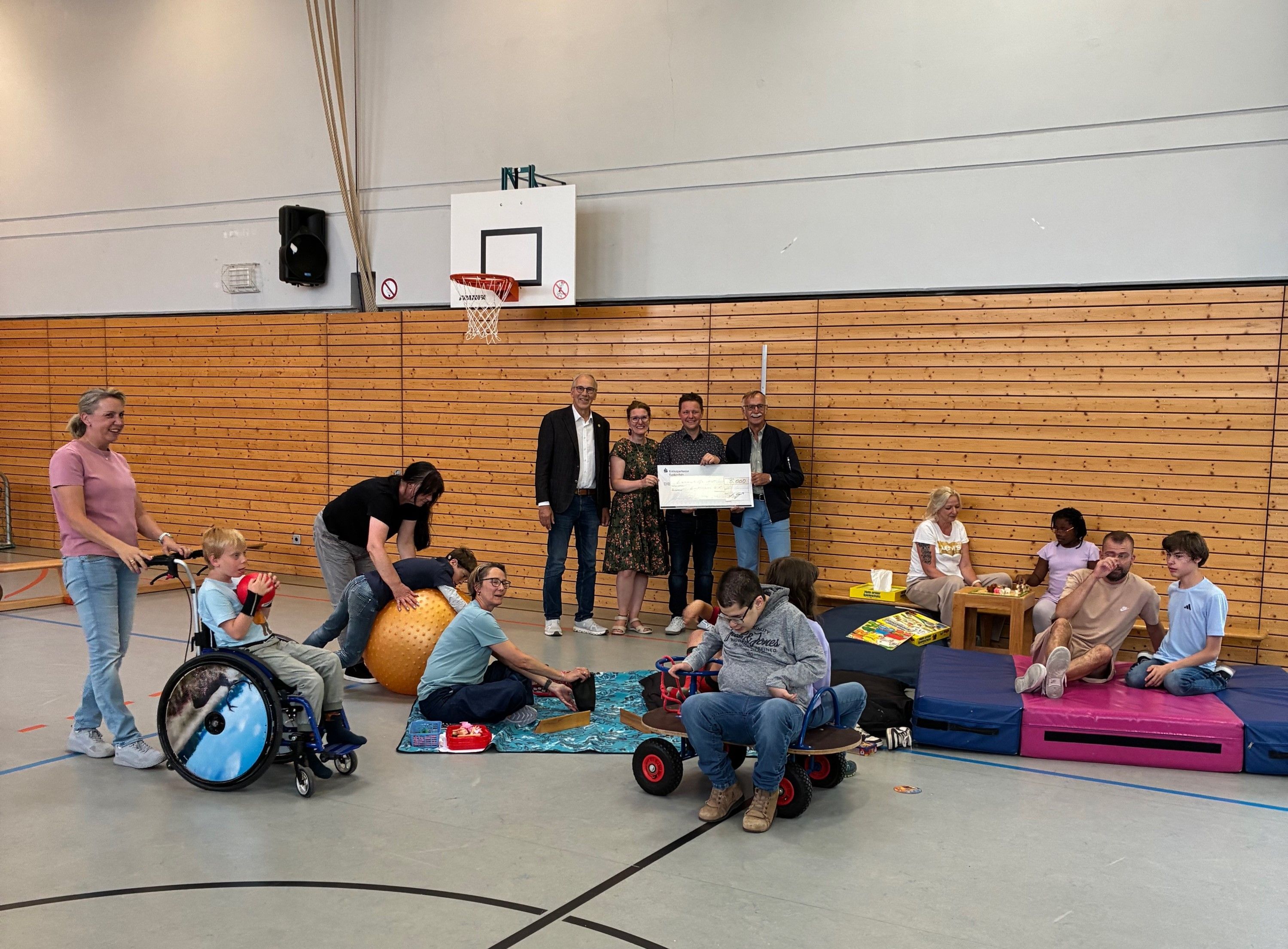 Vertreter des Clubs und der Lebenshilfe halten einen symbolischen Scheck, flankiert von Kindern, Betreuerinnen und Betreuern.
