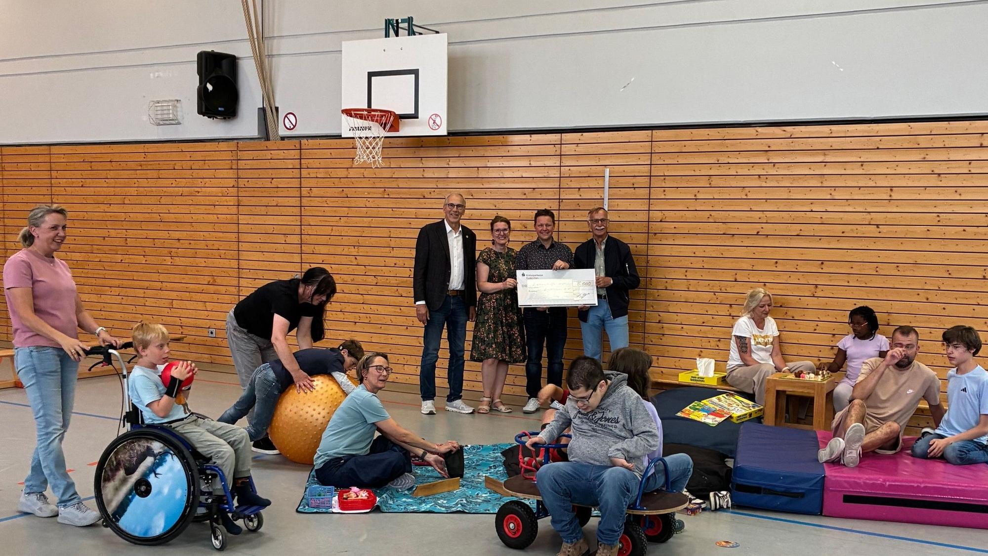 Vertreter des Clubs und der Lebenshilfe halten einen symbolischen Scheck, flankiert von Kindern, Betreuerinnen und Betreuern.
