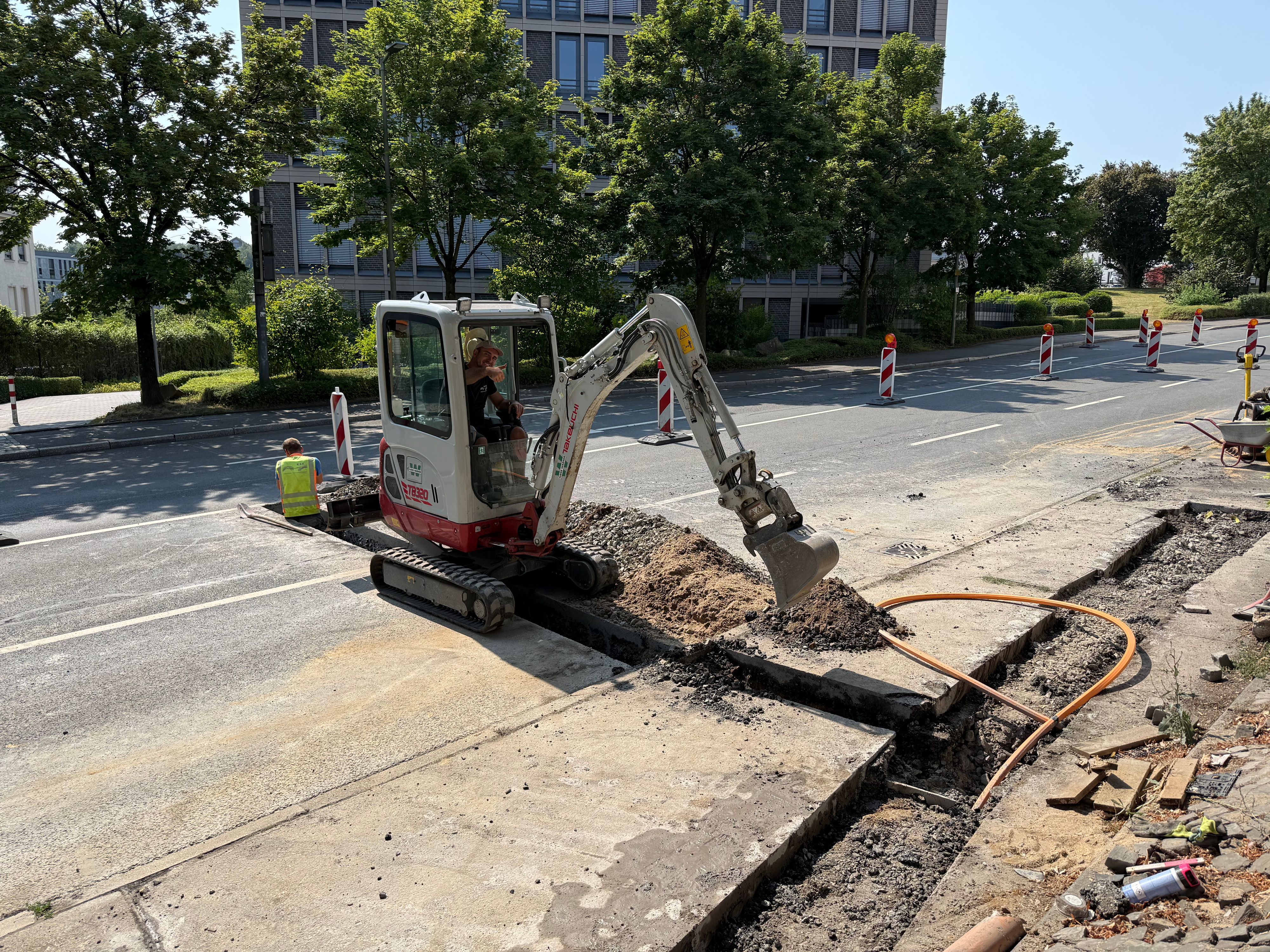 Ein Arbeiter sitz im Bagger und arbeitet auf der Straße.