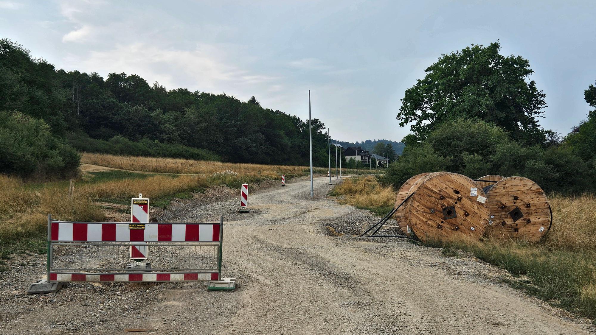 Das Foto zeigt die Baustraße, einige Warnbaken und Rollen mit Kabelleitungen.