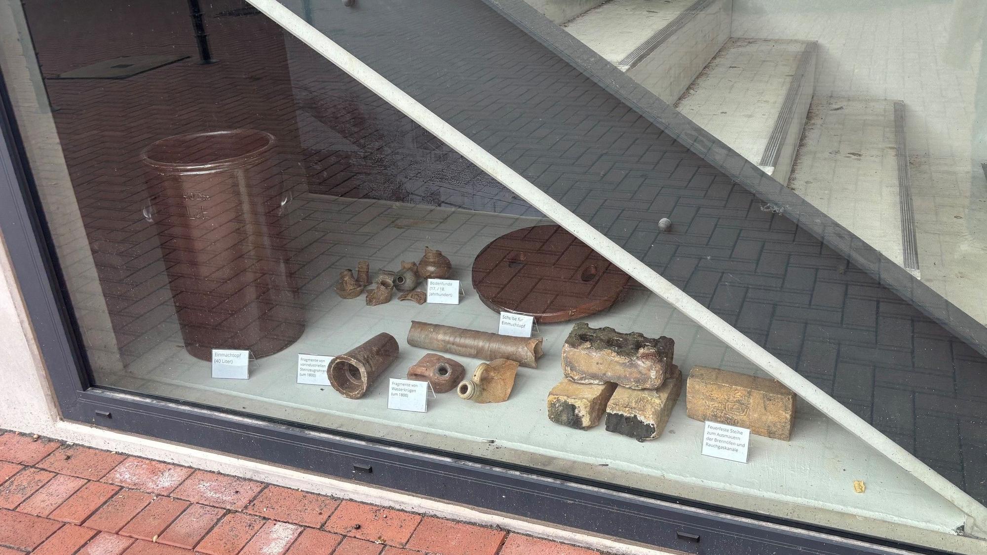 Durch ein Fenster sieht man eine Treppe und Ausstellungsstücke.