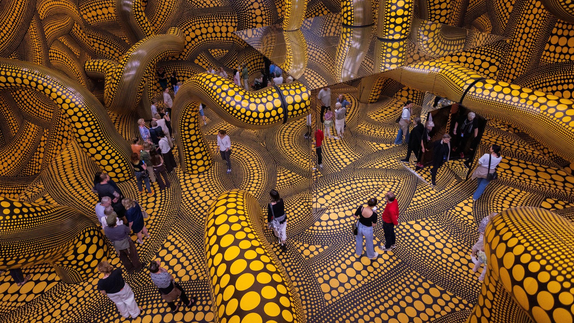 Besucher gehen durch eine Installation mit gelb gepunkteten Tentakeln im Kölner Museum Ludwig.