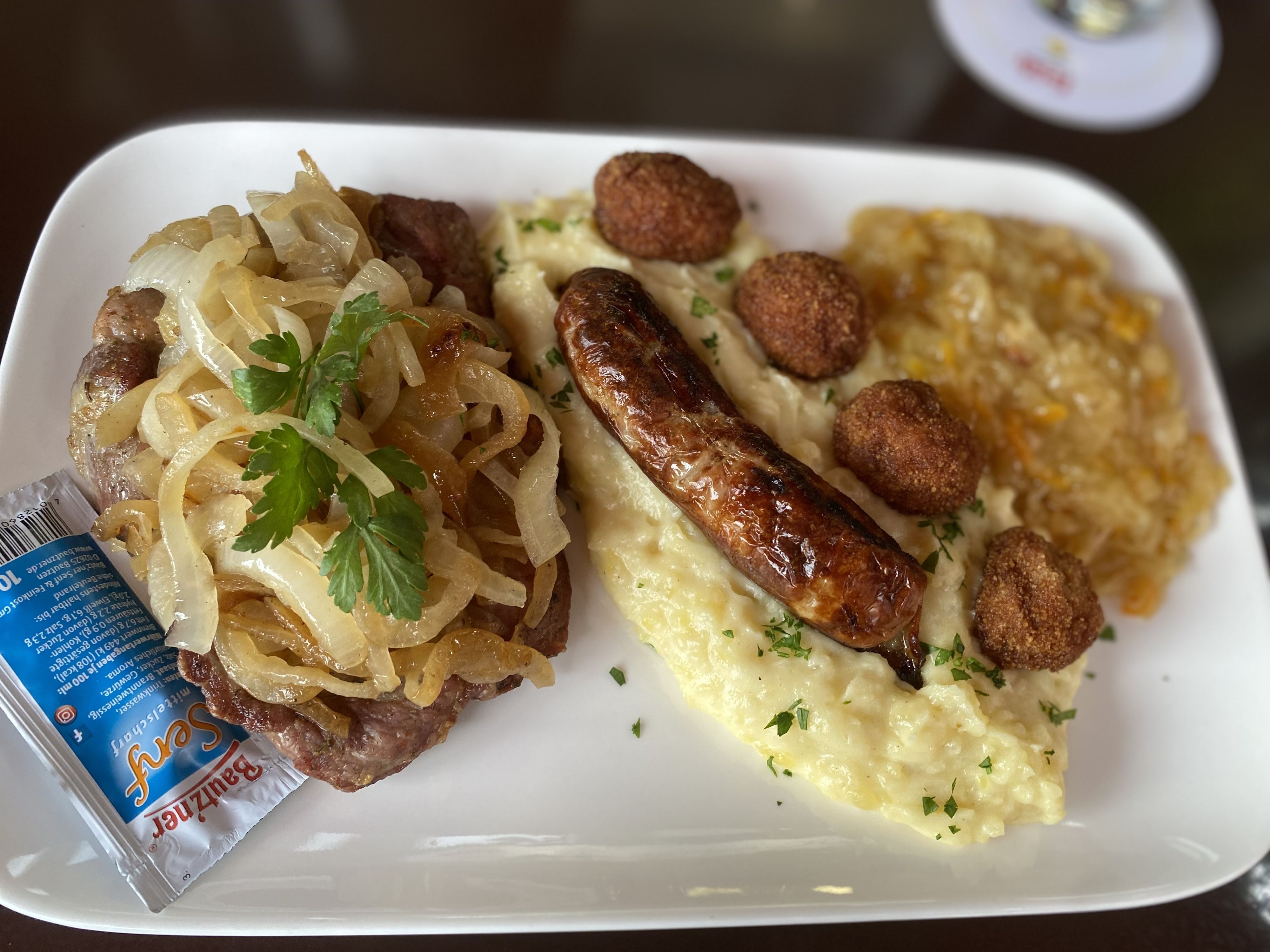 Ein Bestseller, das Thüringer Allerlei: kleine Thüringer Bratwurst, vier Bratwurst-Pralinen, Rostbrätel (marinierte Schweinenackensteaks, Gewürzmischung von Thomas Richter) mit Schmorzwiebeln, dazu Kartoffelstampf und Sauerkraut nach Oma Christas Rezept.