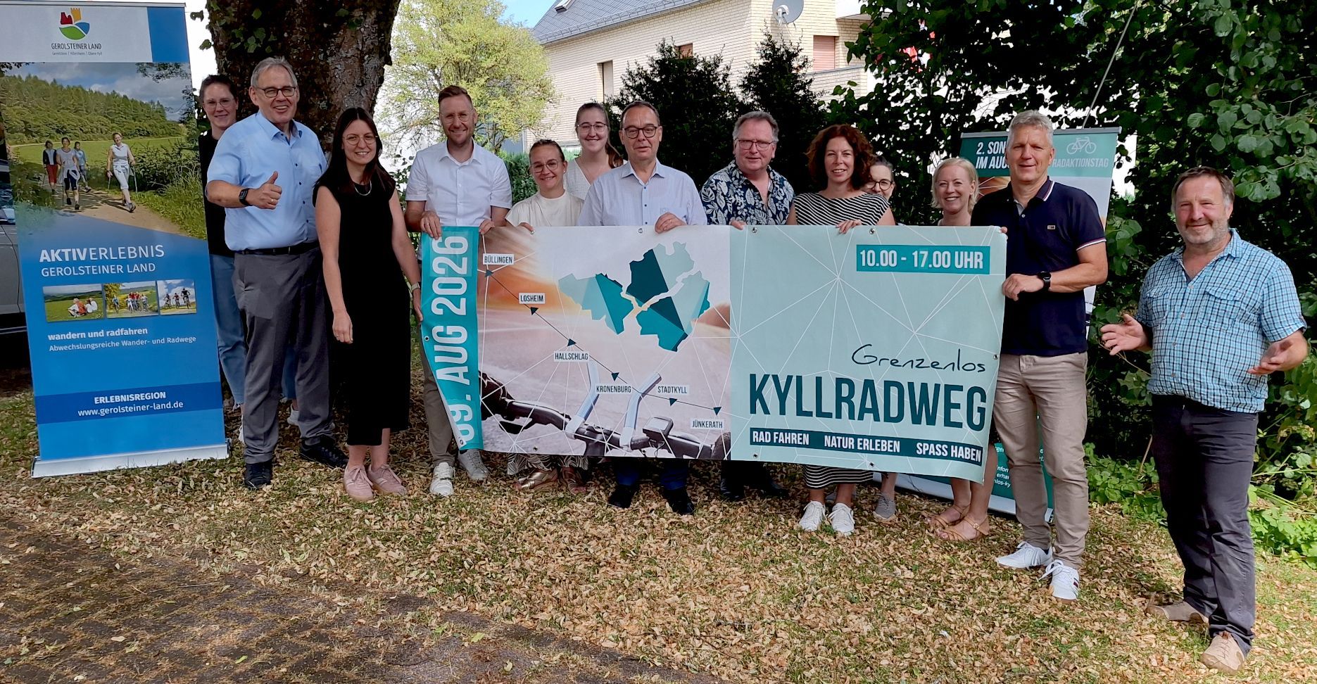 Die Genannten halten ein großes Banner mit der Aufschrift: „Kyllradweg“ in die Kamera.