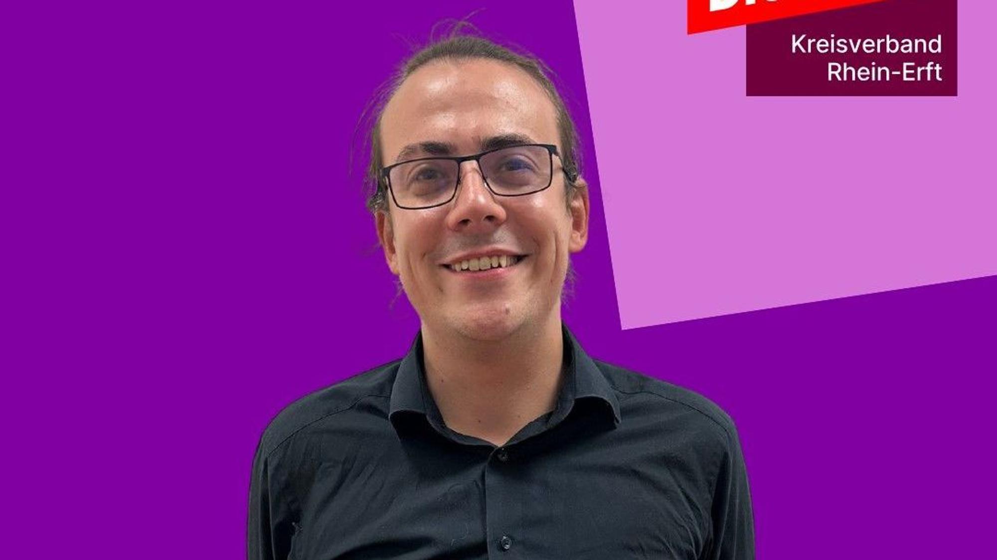 Das Bild zeigt den Kandidaten. Er trägt ein dunkles Hemd und eine Brille.