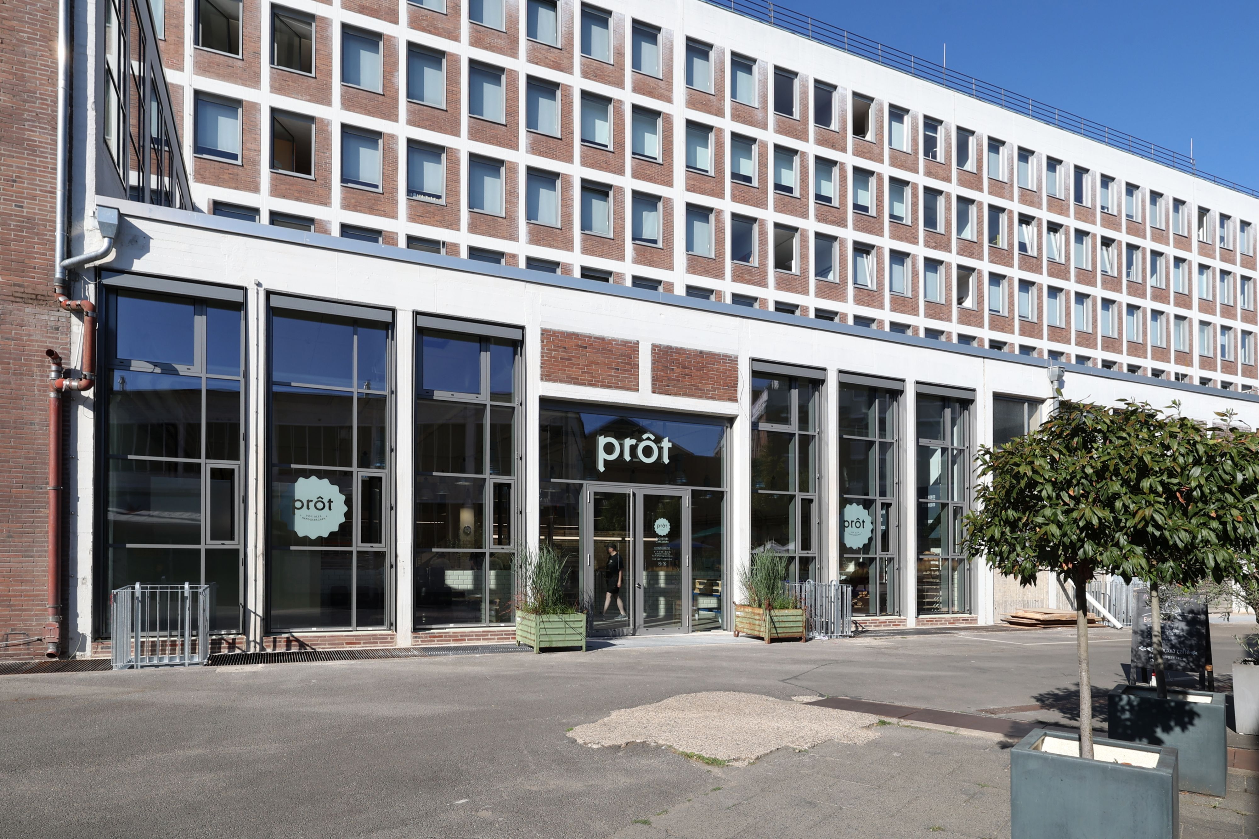 Auf der Glasfront eines Gebäudes prangt der Schriftzug Prôt.